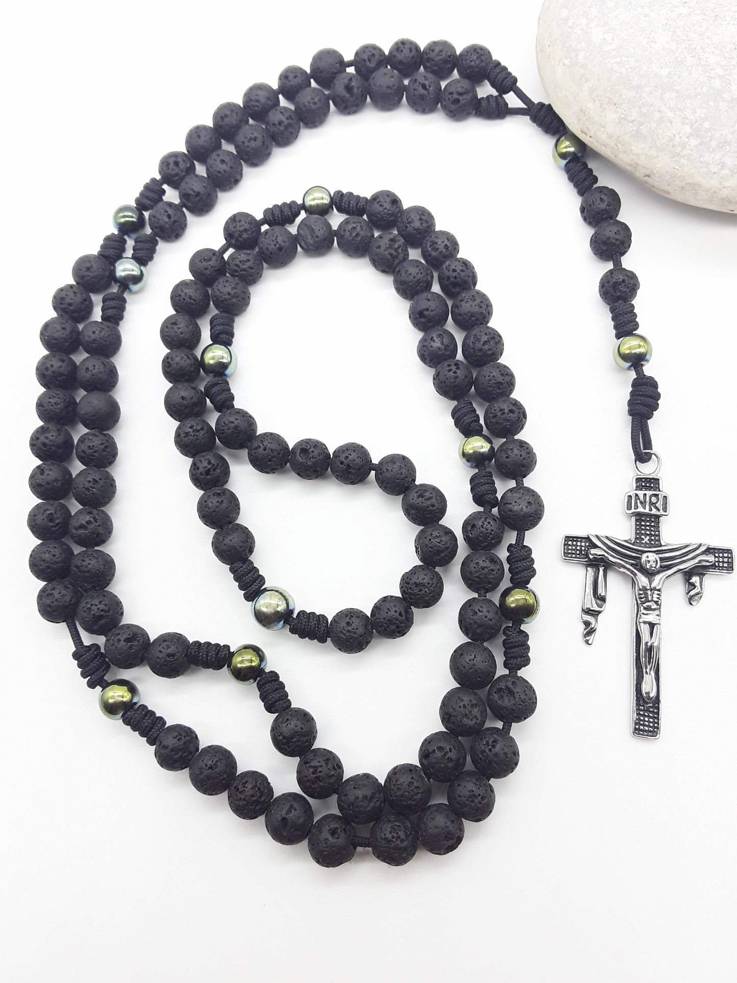 Steadfast Path lava stone and hematite 10-decade Catholic rosary with stainless steel crucifix beside stone by Polmadeva