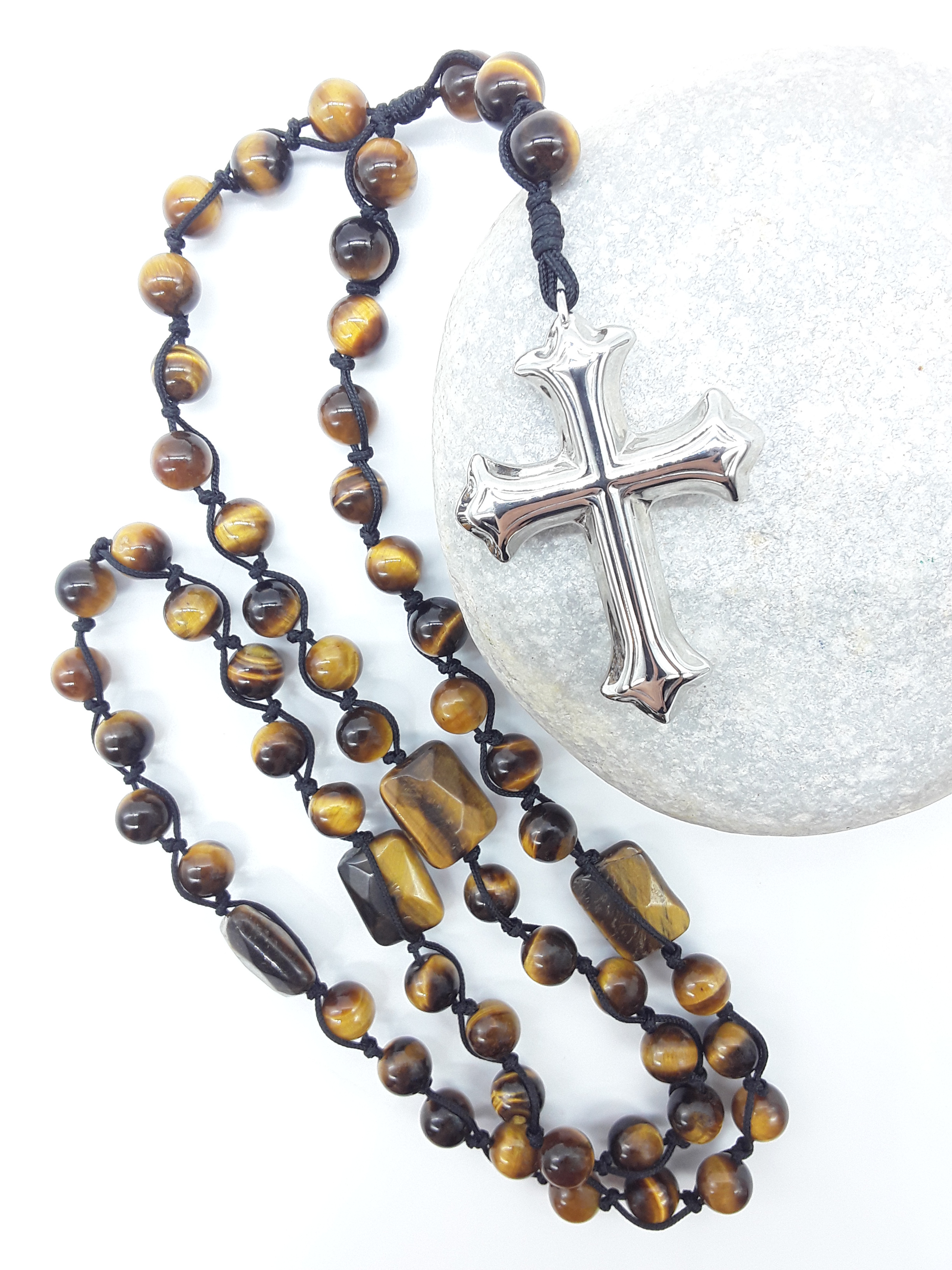 Steady Flame — Tiger’s Eye Catholic Rosary (10 Decade) by Polmadeva resting on natural stone surface with stainless steel cross.