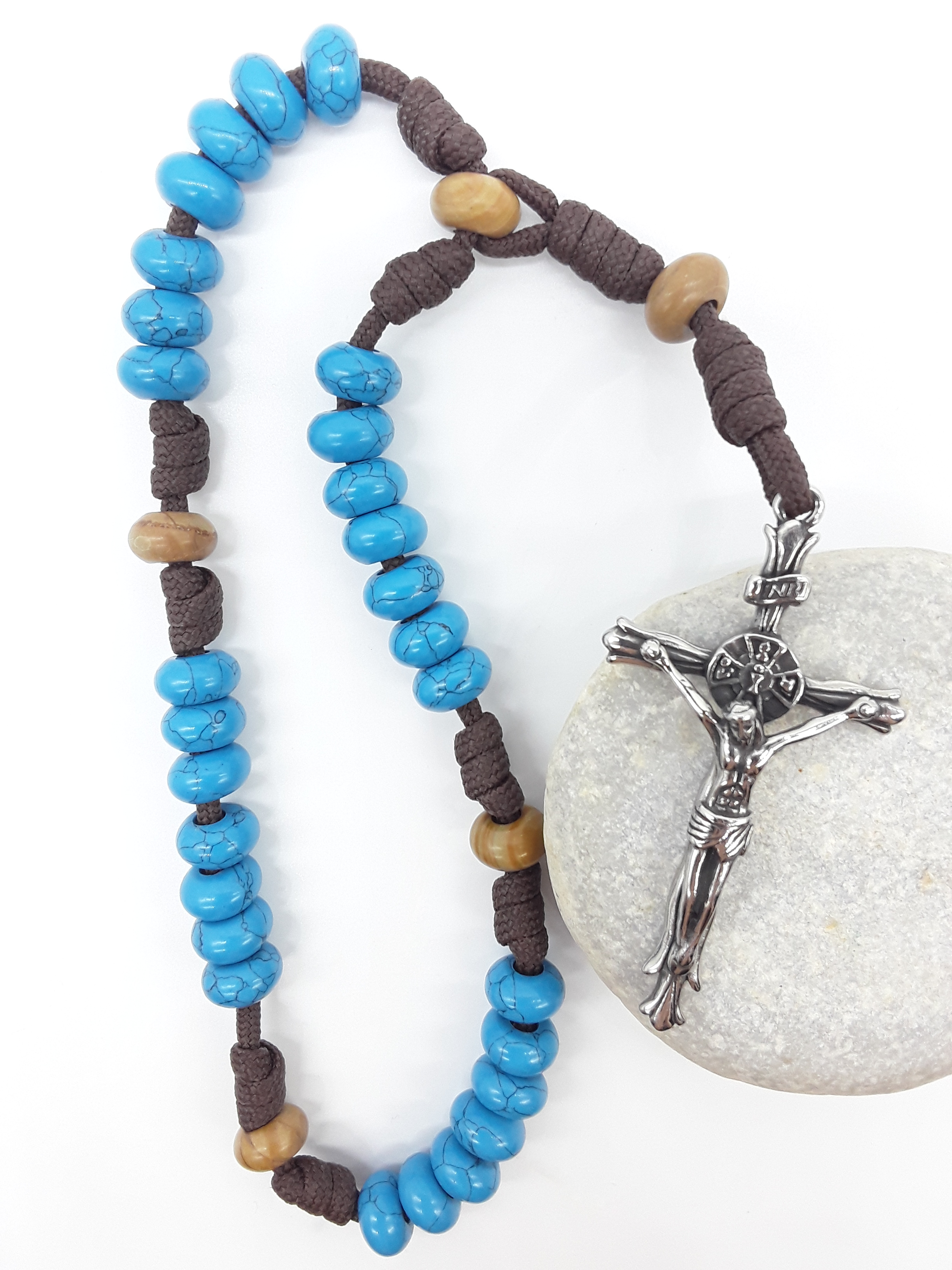 The Anchored Way Paracord Anglican Prayer Beads by Polmadeva placed on stone, crafted with Turquoise, Wood Lace beads, and stainless steel crucifix