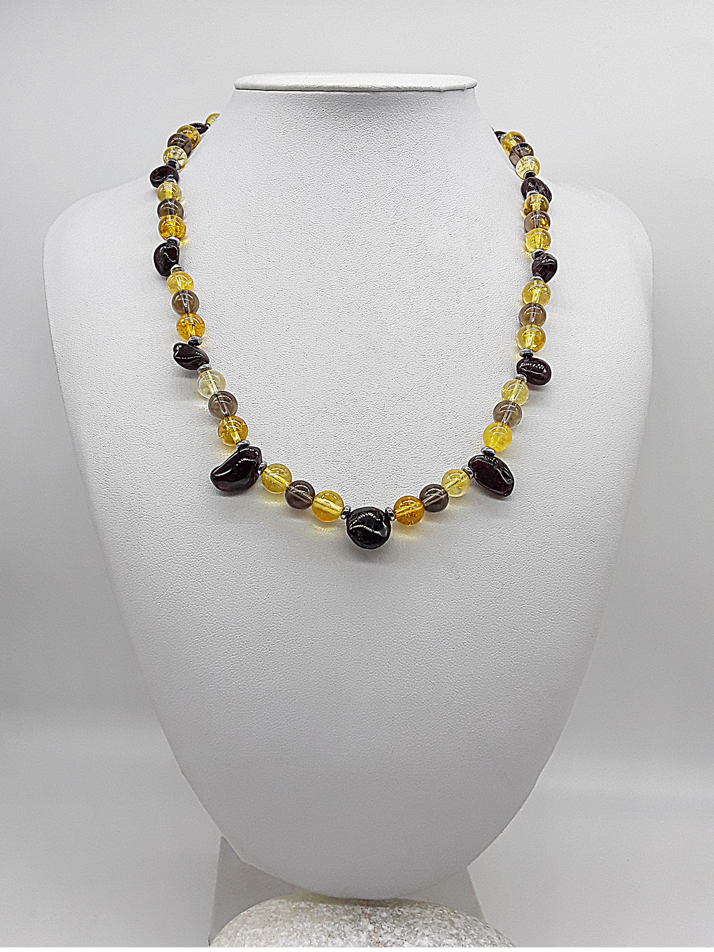 Handmade necklace with citrine, garnet, smoked quartz, and hematite beads displayed on a white mannequin bust.
