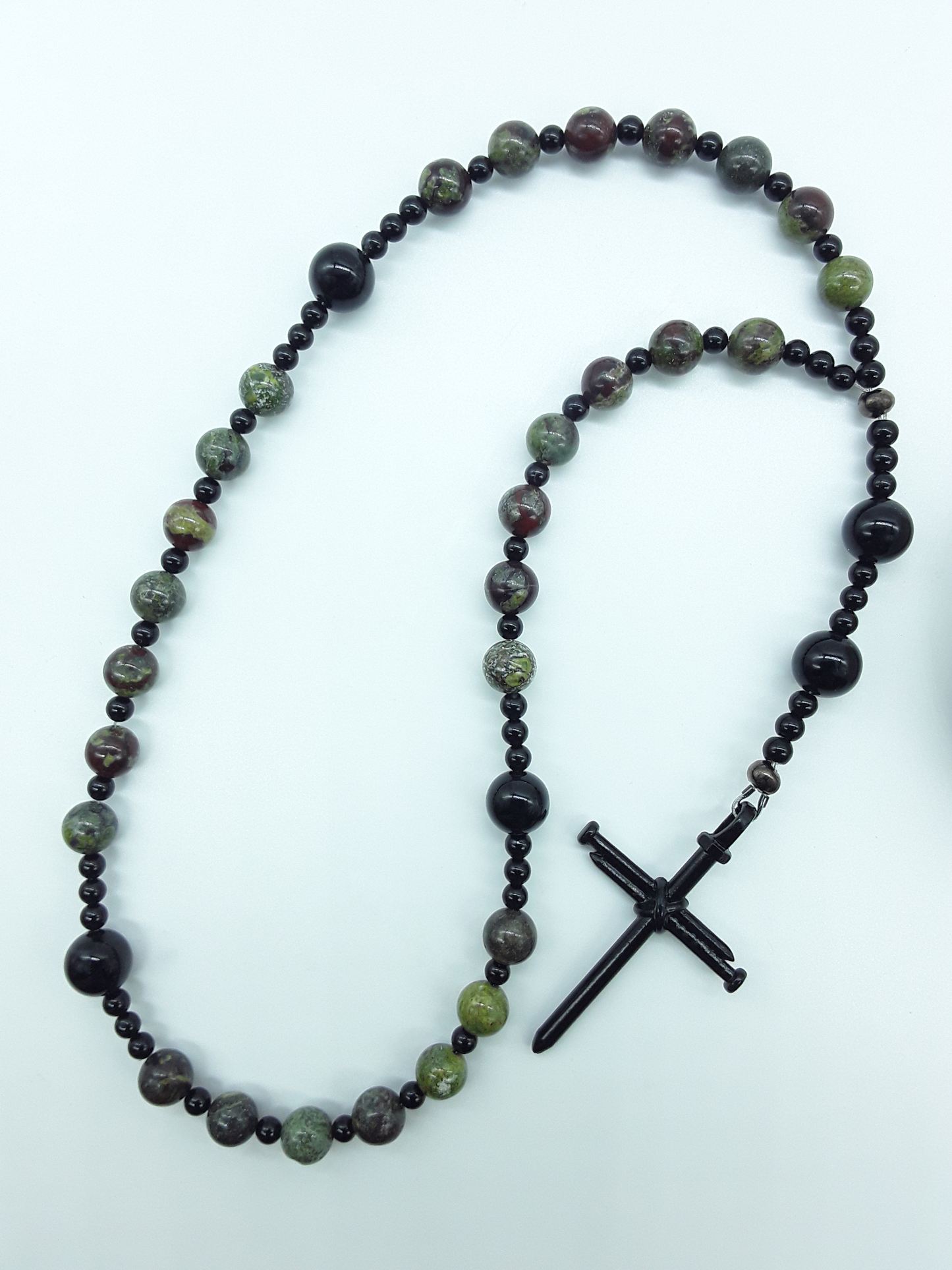 The Enduring Root Anglican Prayer Beads by Polmadeva with Dragon Blood, Black Onyx, and stainless steel nail cross on white background