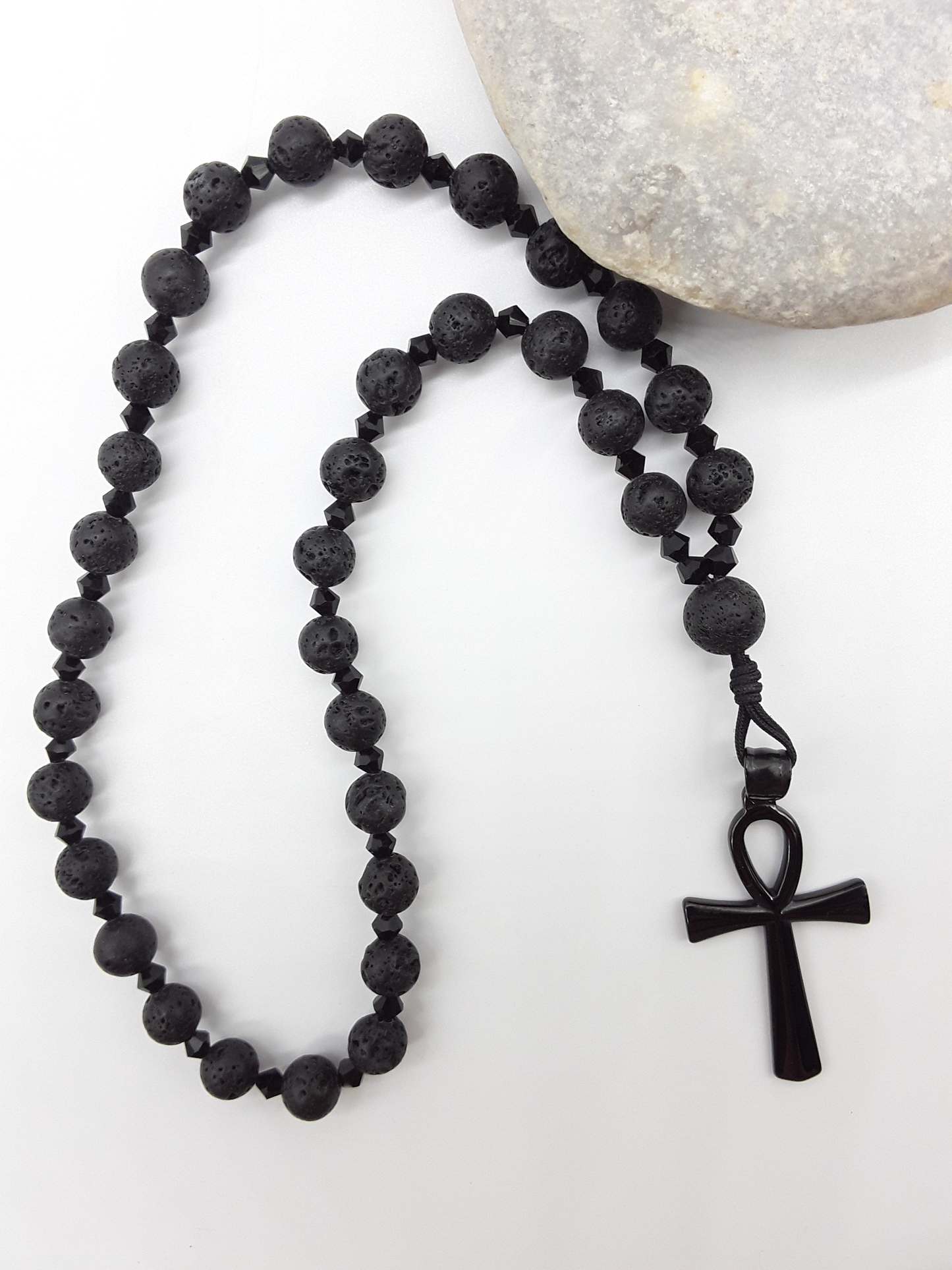Lava and black crystal Orthodox Rosary with Ankh cross beside natural stone surface by Polmadeva.