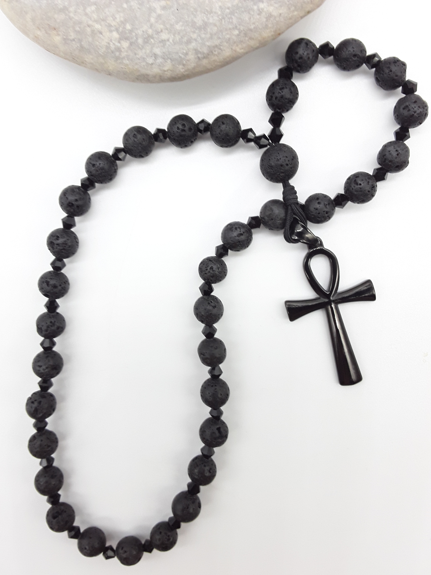 Lava and black crystal Orthodox Rosary with Ankh cross beside natural stone surface by Polmadeva.