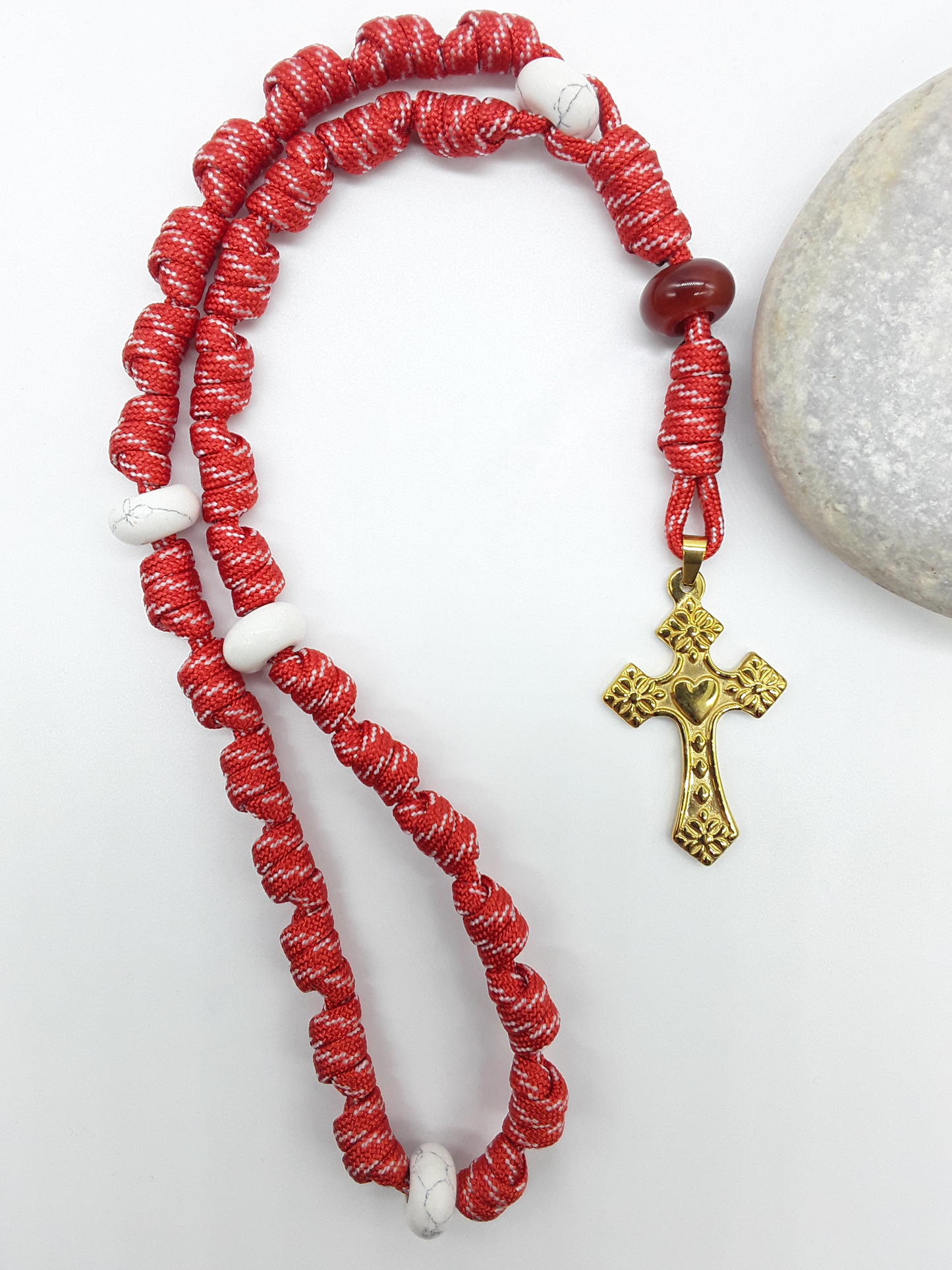 Knotted Anglican Rosary with Carnelian and Howlite elements and Golden Heart Cross placed beside white stone on white background, Polmadeva