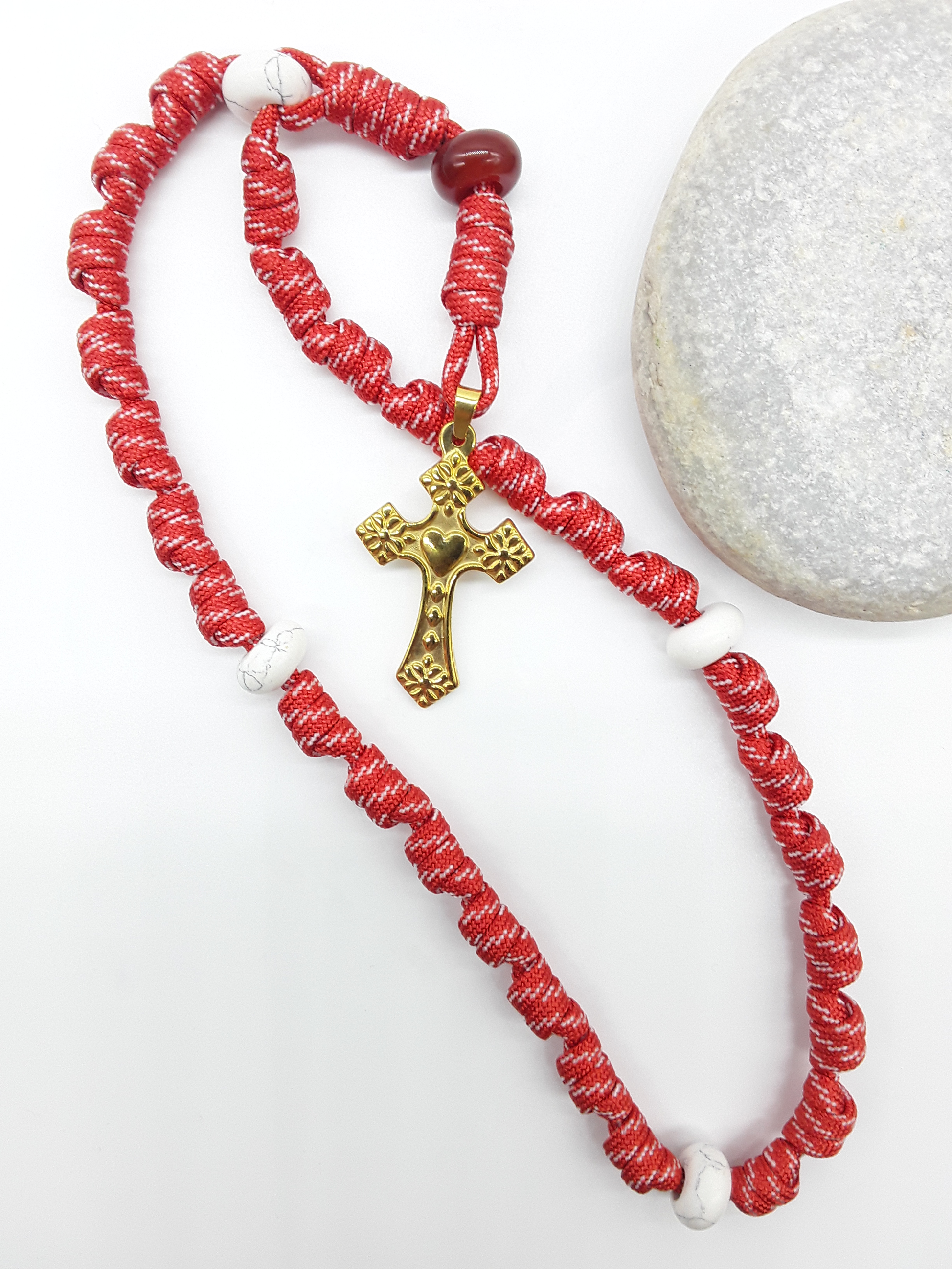 Knotted Anglican Rosary with Carnelian and Howlite elements and Golden Heart Cross placed beside white stone on white background, Polmadeva