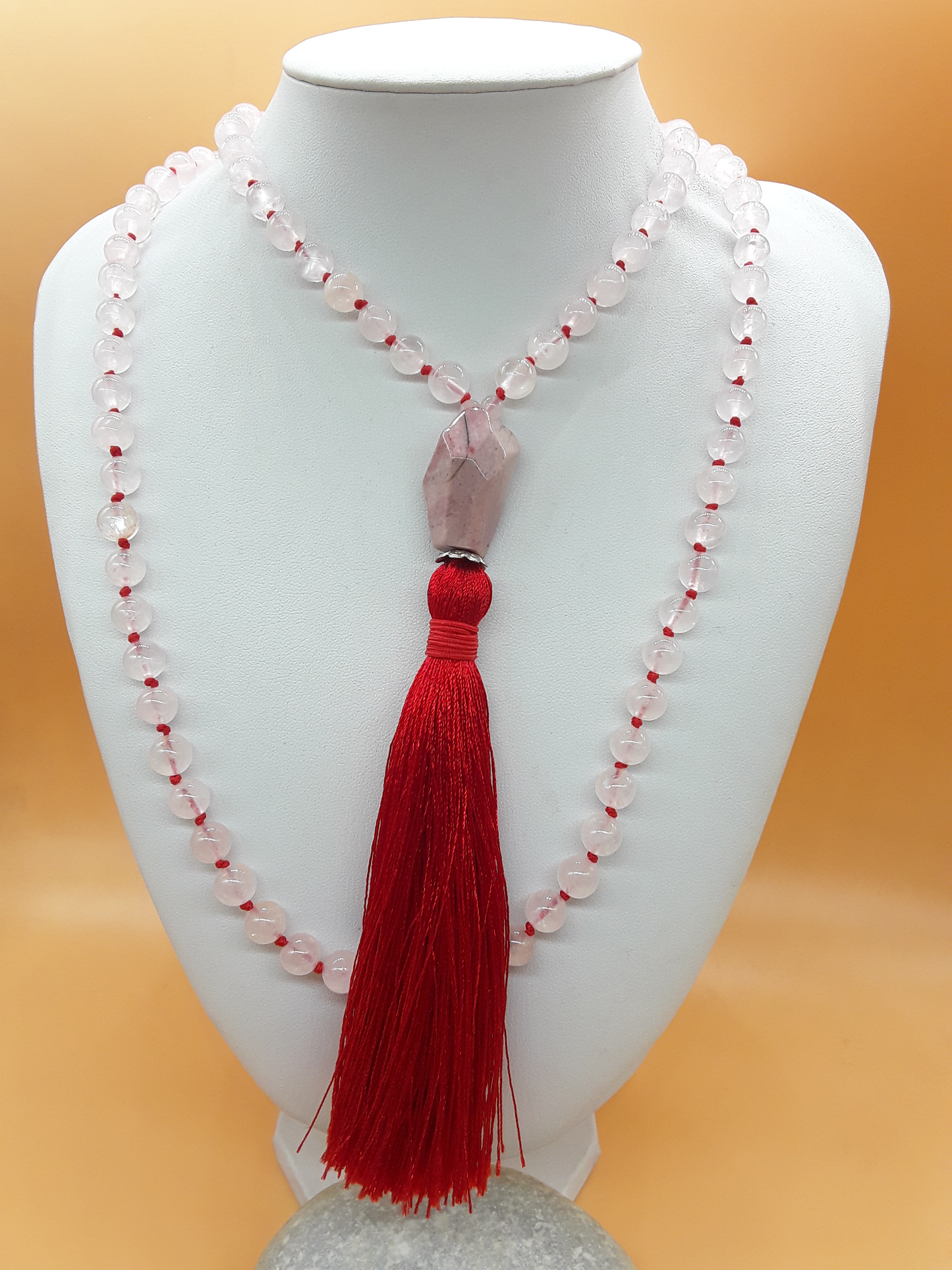 Necklace with red tassel on a white mannequin against an orange background by Polmadeva