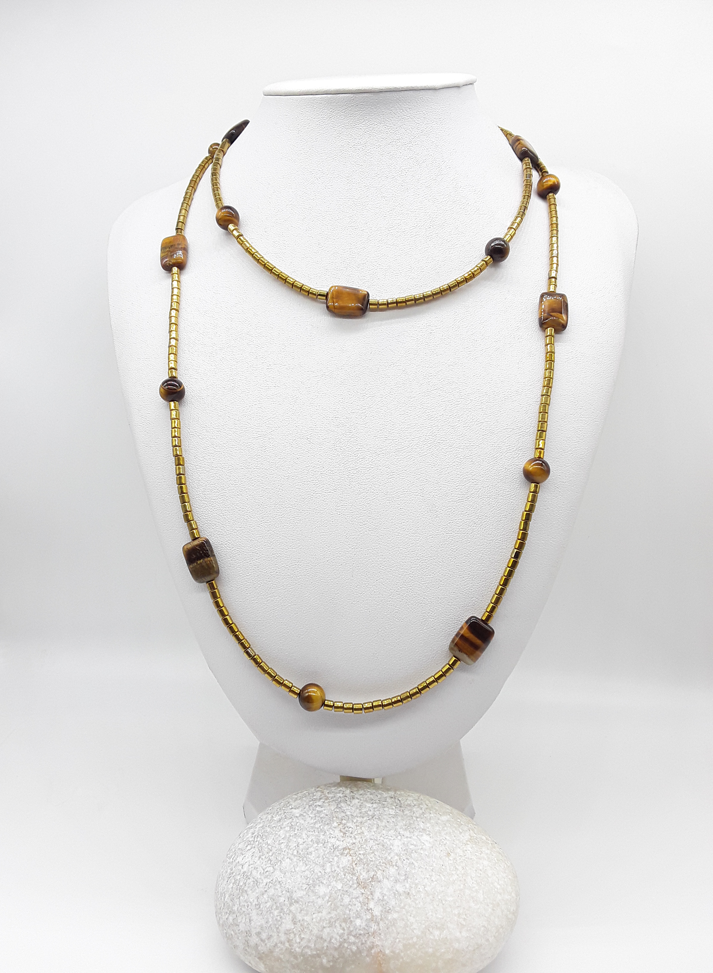 Long gold-toned beaded necklace with Tiger’s Eye and hematite beads displayed on a white mannequin bust.
