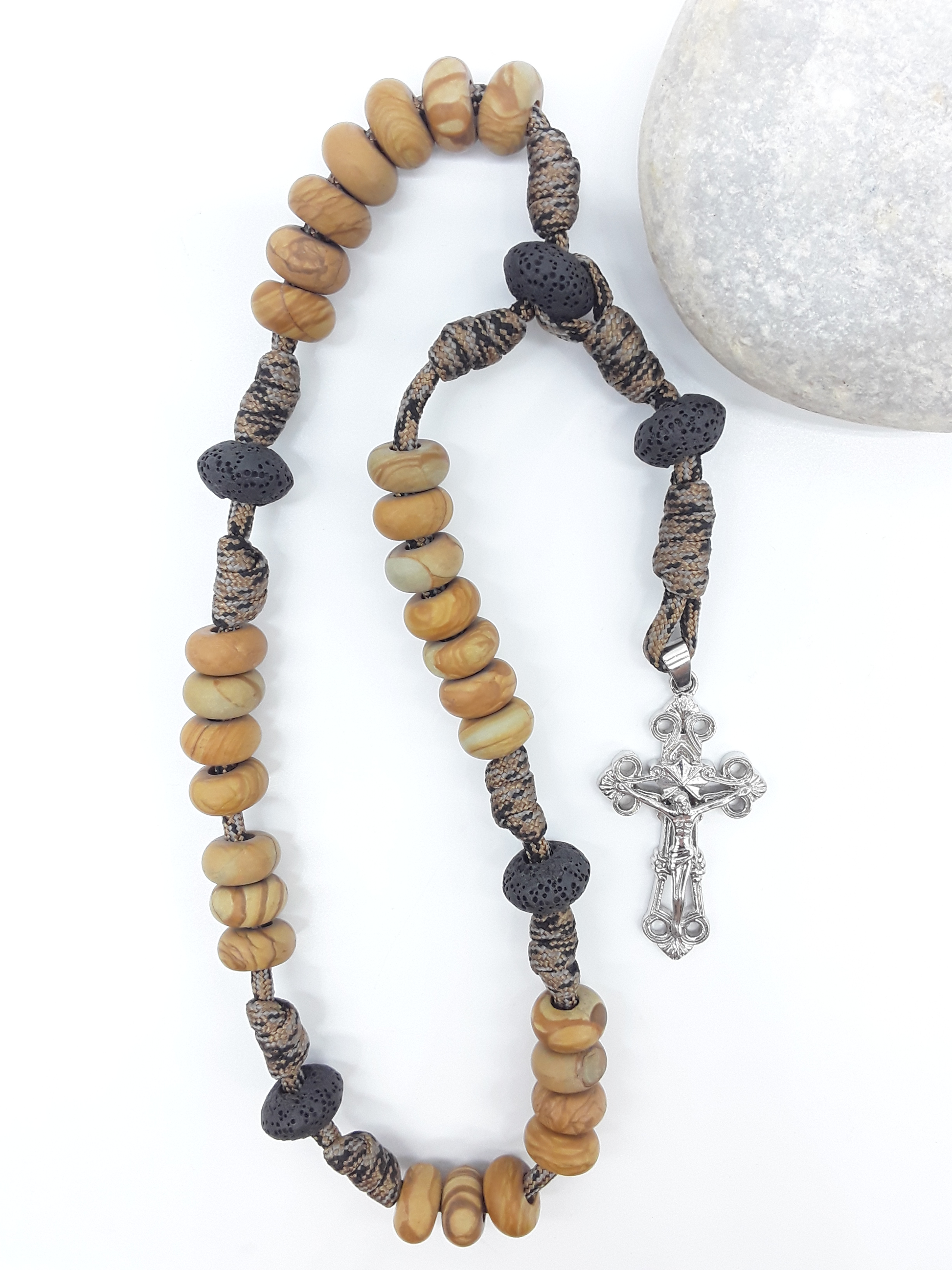 The Grounded Path — Natural Wood and Lava Stone Paracord Anglican Prayer Beads with stainless steel Cross by Polmadeva beside natural stone.