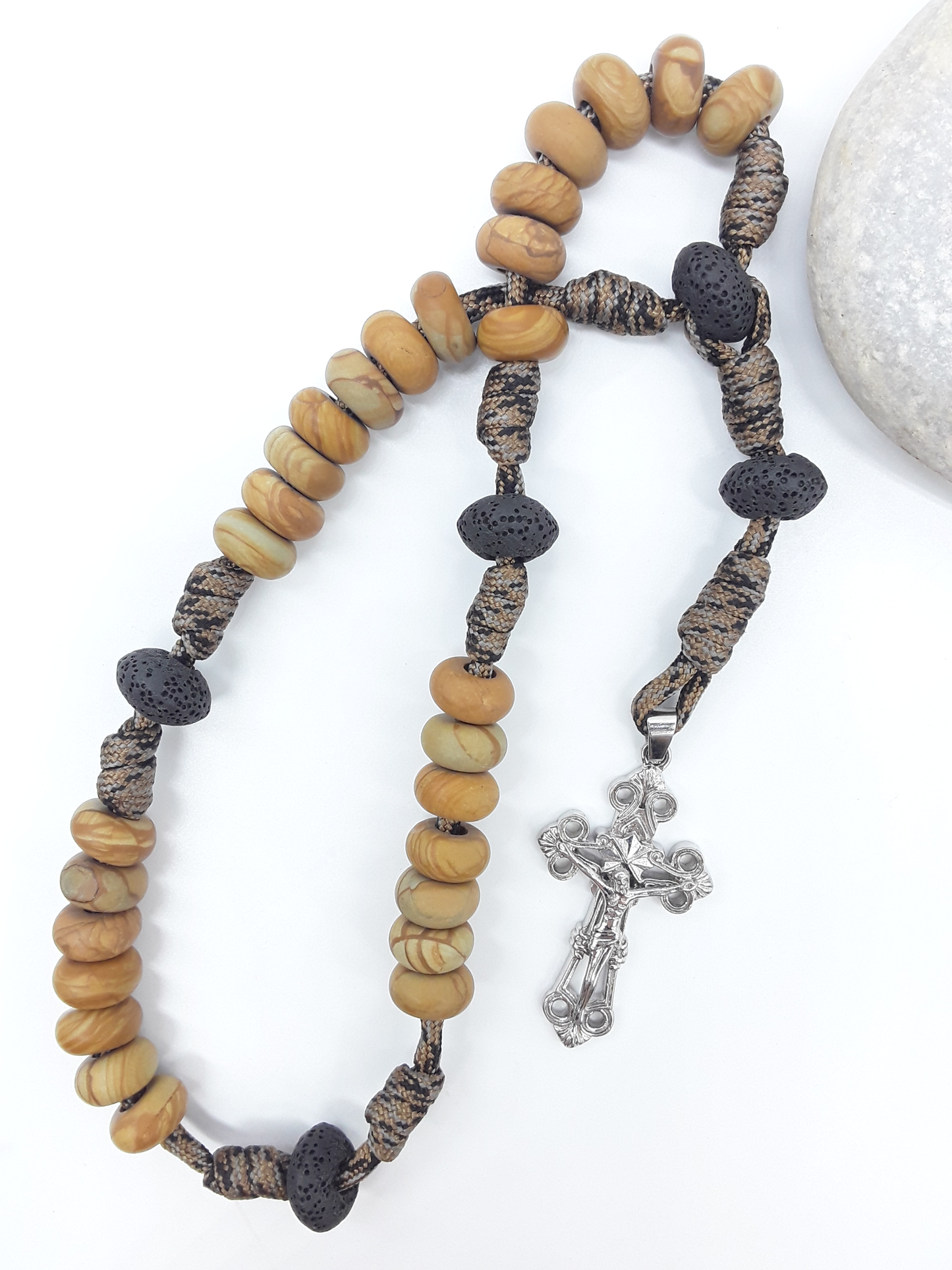 The Grounded Path — Natural Wood and Lava Stone Paracord Anglican Prayer Beads with stainless steel Cross by Polmadeva beside natural stone.