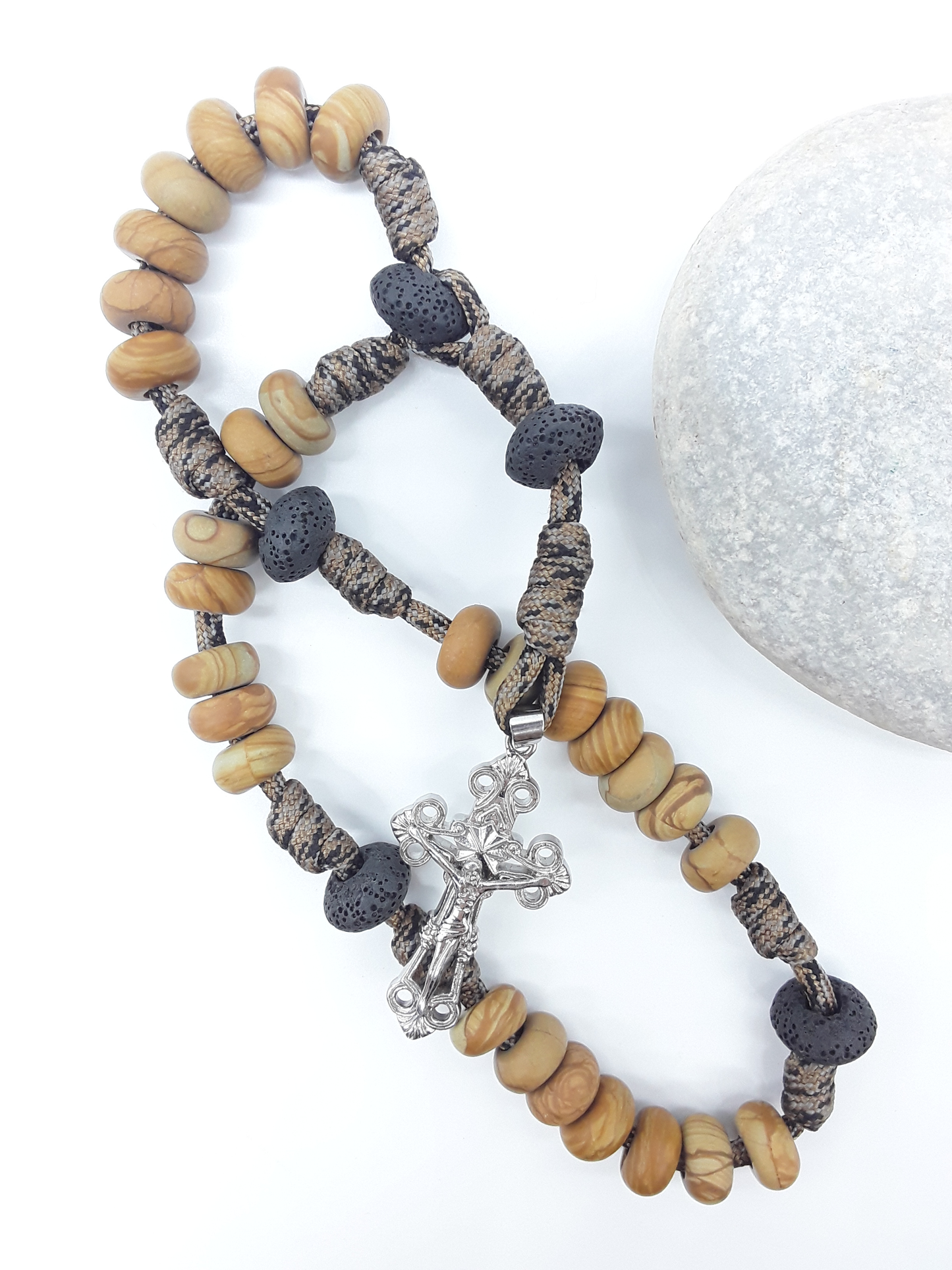 The Grounded Path — Natural Wood and Lava Stone Paracord Anglican Prayer Beads with stainless steel Cross by Polmadeva beside natural stone.