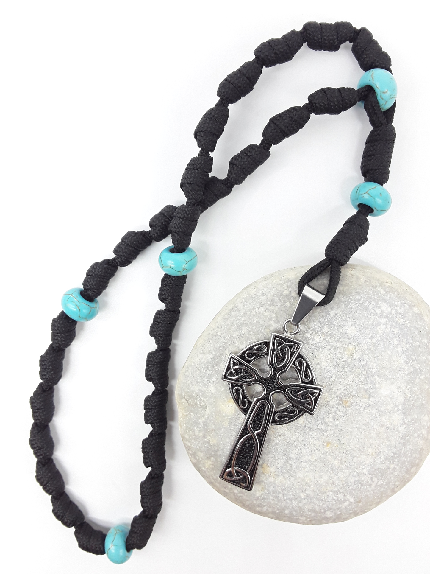 The Guiding Tide Celtic Trinity Anglican Rosary by Polmadeva with hand-knotted black paracord, Turquoise elements, and Celtic Trinity Cross on stone.
