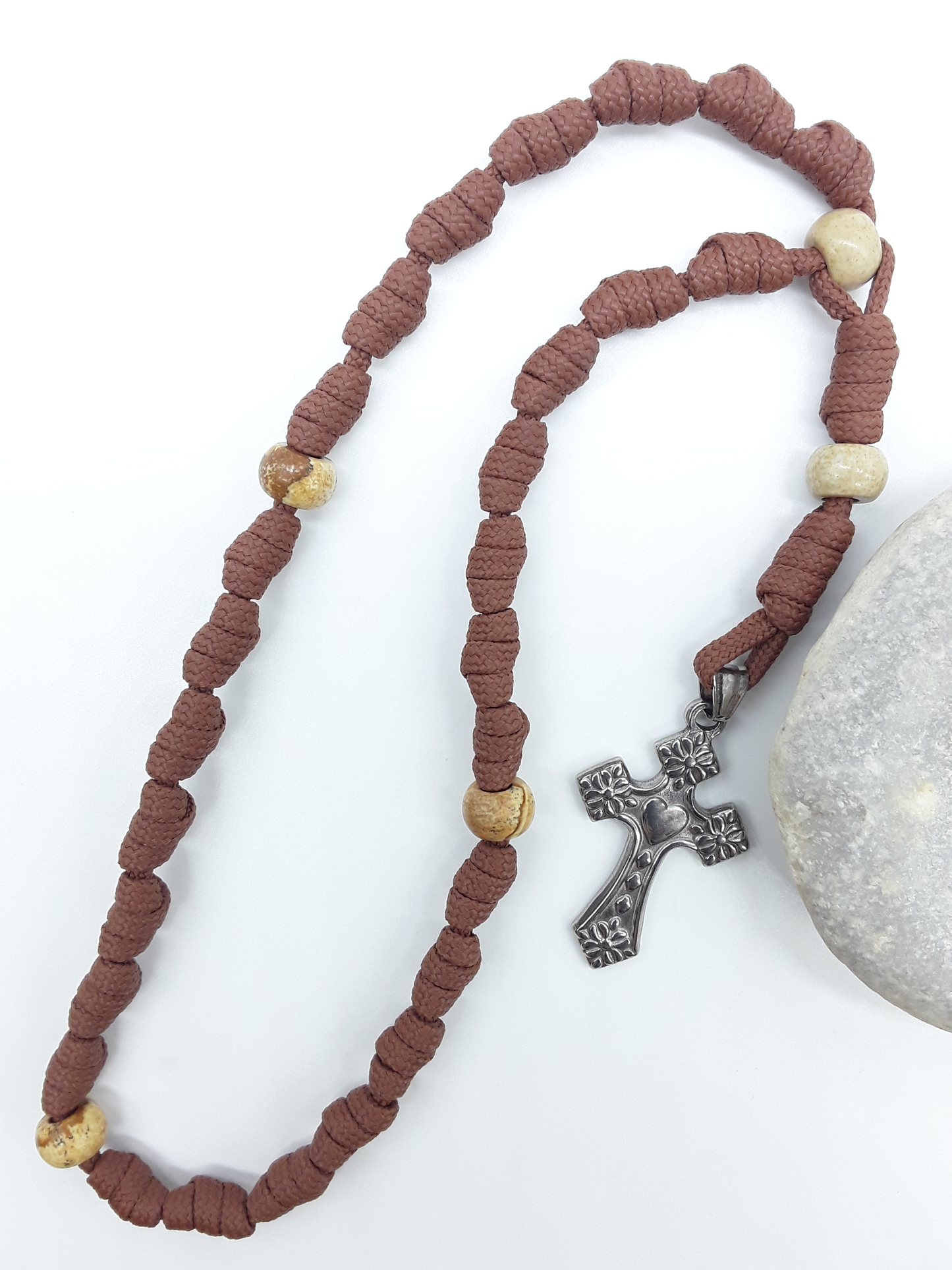 Knotted Anglican Rosary with Jasper elements and floral stainless steel cross displayed on white background beside white stone, Polmadeva