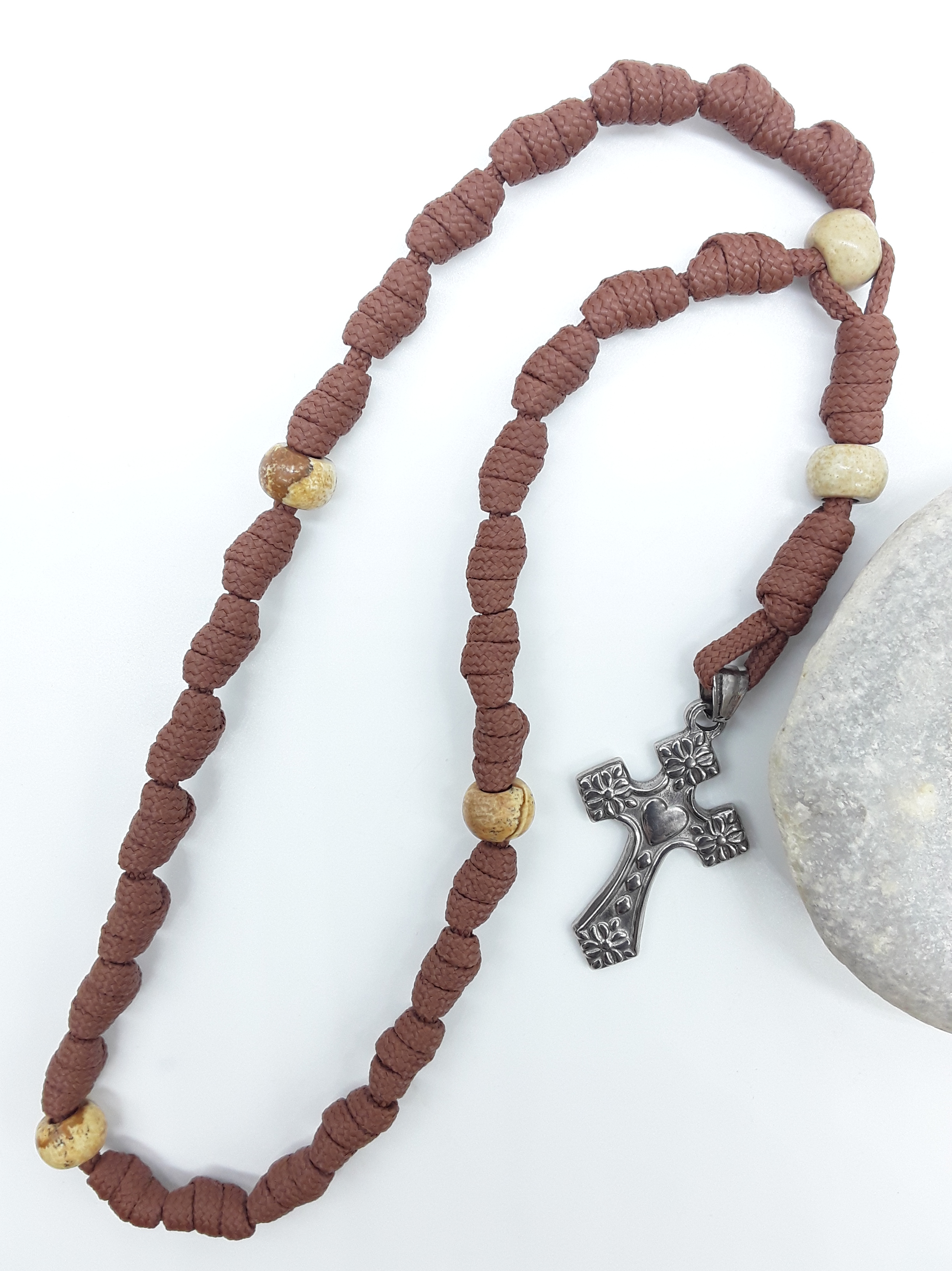 Knotted Anglican Rosary with Jasper elements and floral stainless steel cross displayed on white background beside white stone, Polmadeva