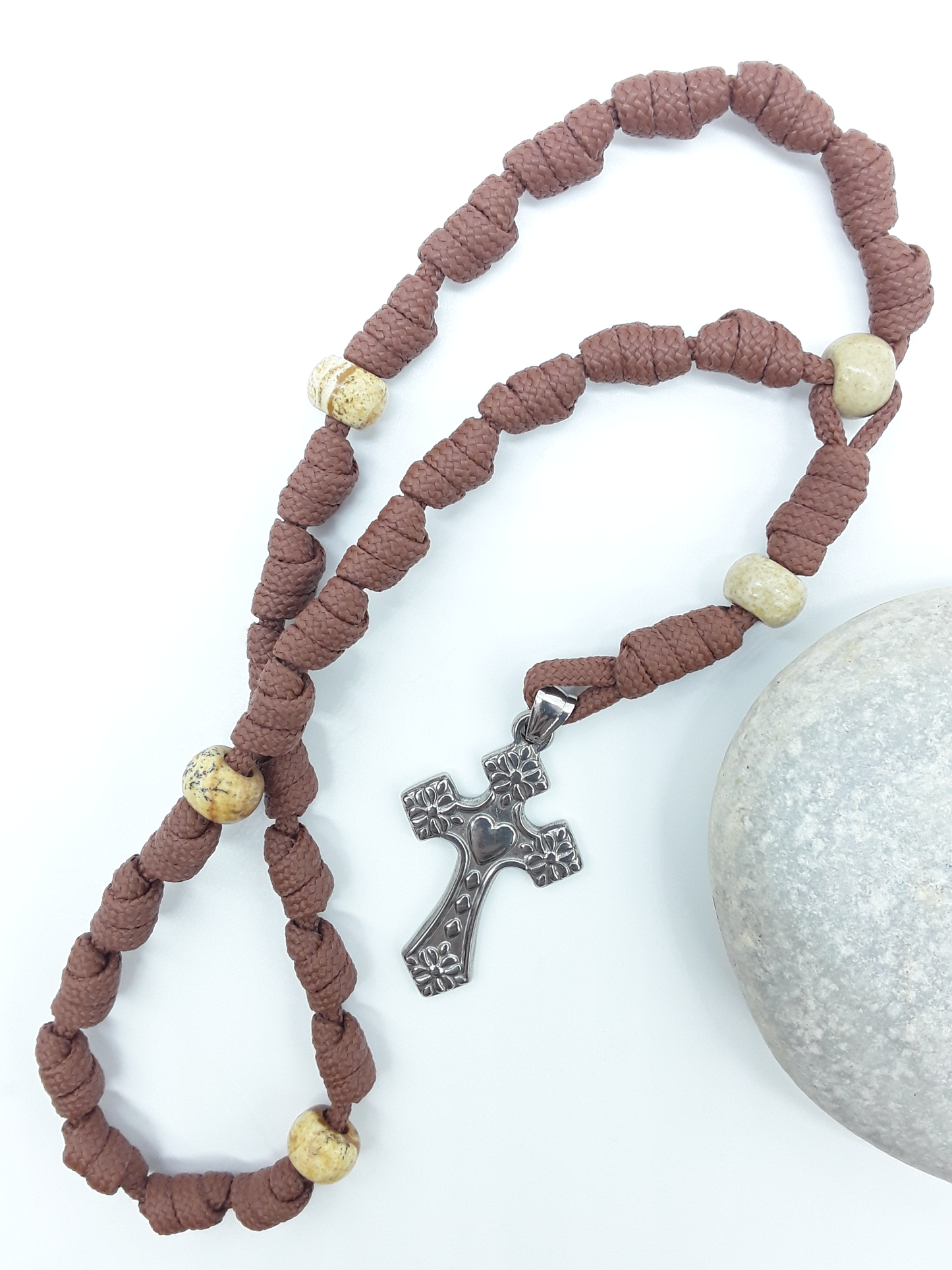 Knotted Anglican Rosary with Jasper elements and floral stainless steel cross displayed on white background beside white stone, Polmadeva