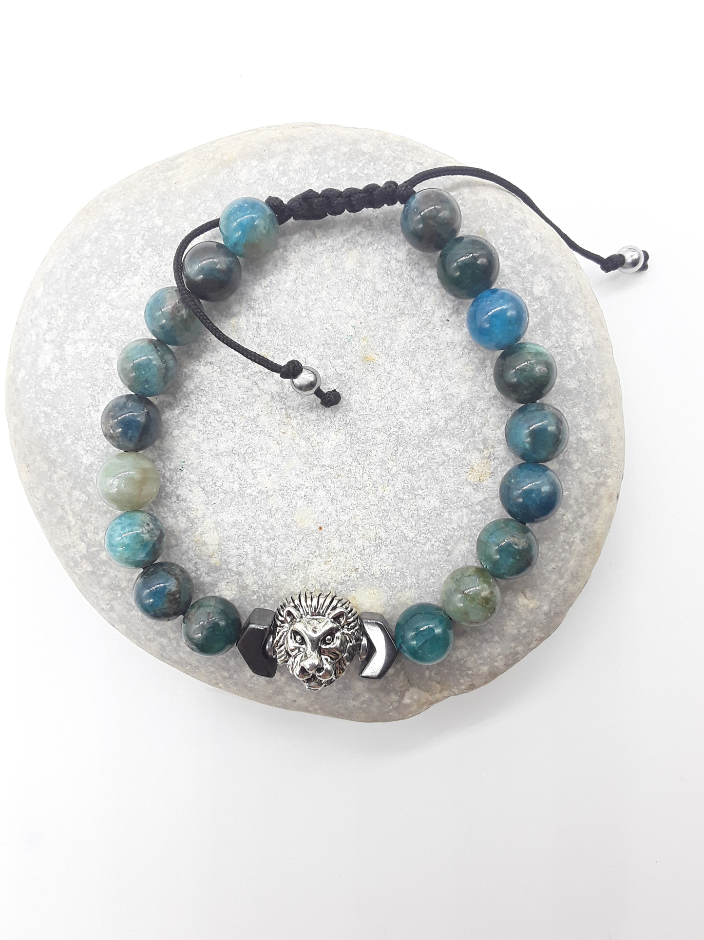 The Inner Course Lion Bracelet by Polmadeva placed on natural stone, featuring apatite beads, hematite arrow, and lion centerpiece