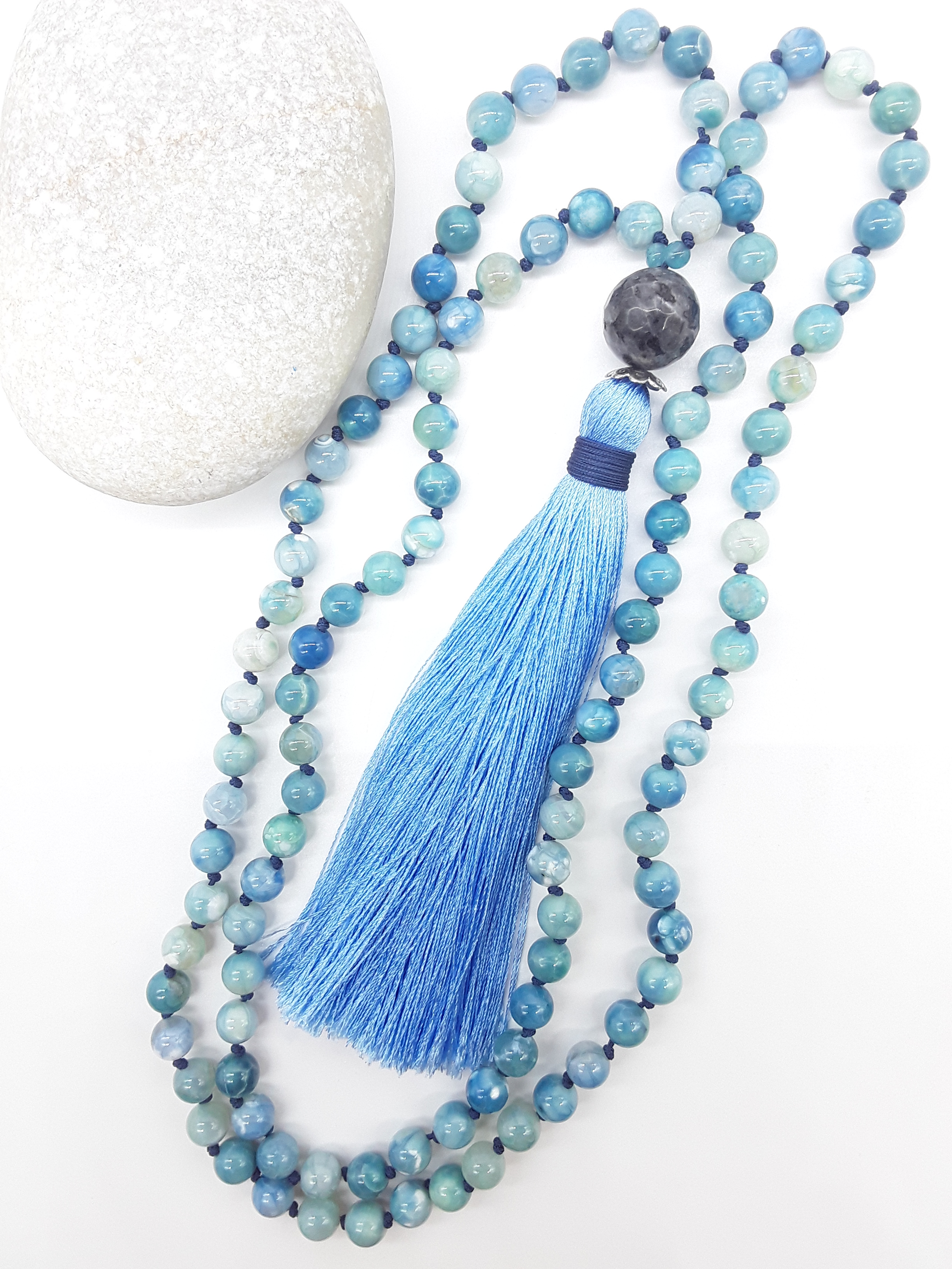 Agate and Labradorite Mala Beads with blue tassel placed beside white stone on white background, Polmadeva