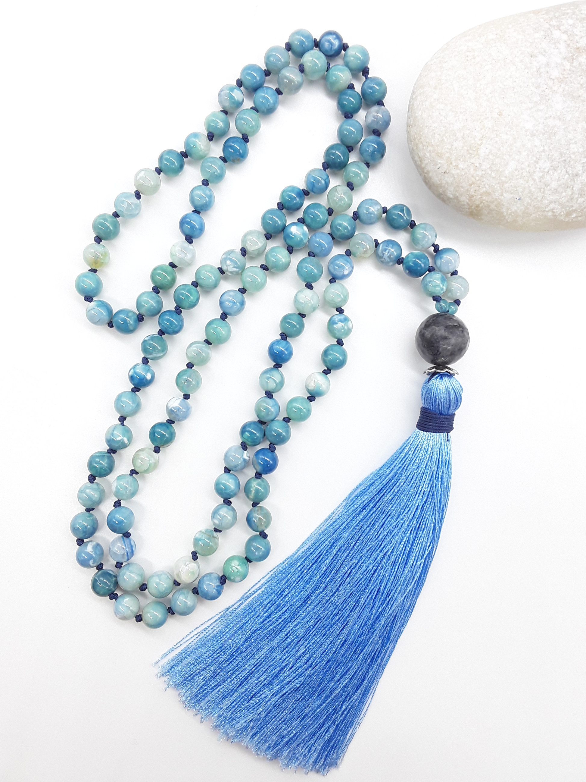 Agate and Labradorite Mala Beads with blue tassel placed beside white stone on white background, Polmadeva