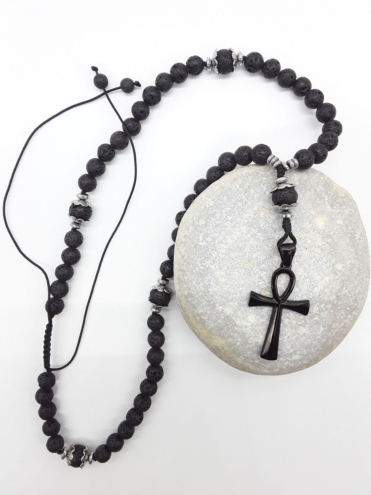 Lava and steel Orthodox Rosary with black Ankh cross and adjustable cord resting on natural stone surface by Polmadeva.