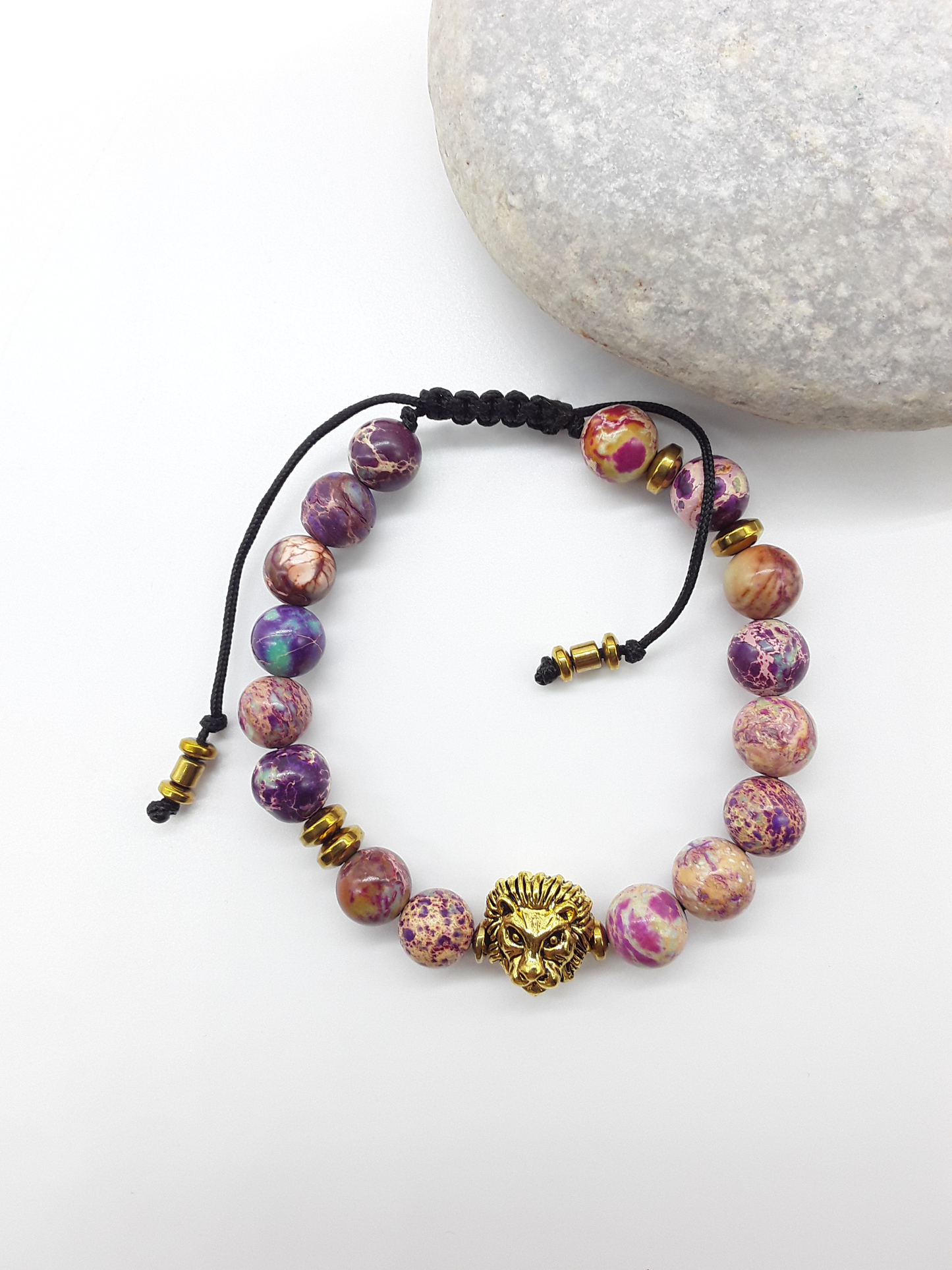 Beaded lion bracelet with imperial jasper stones placed beside natural rocks