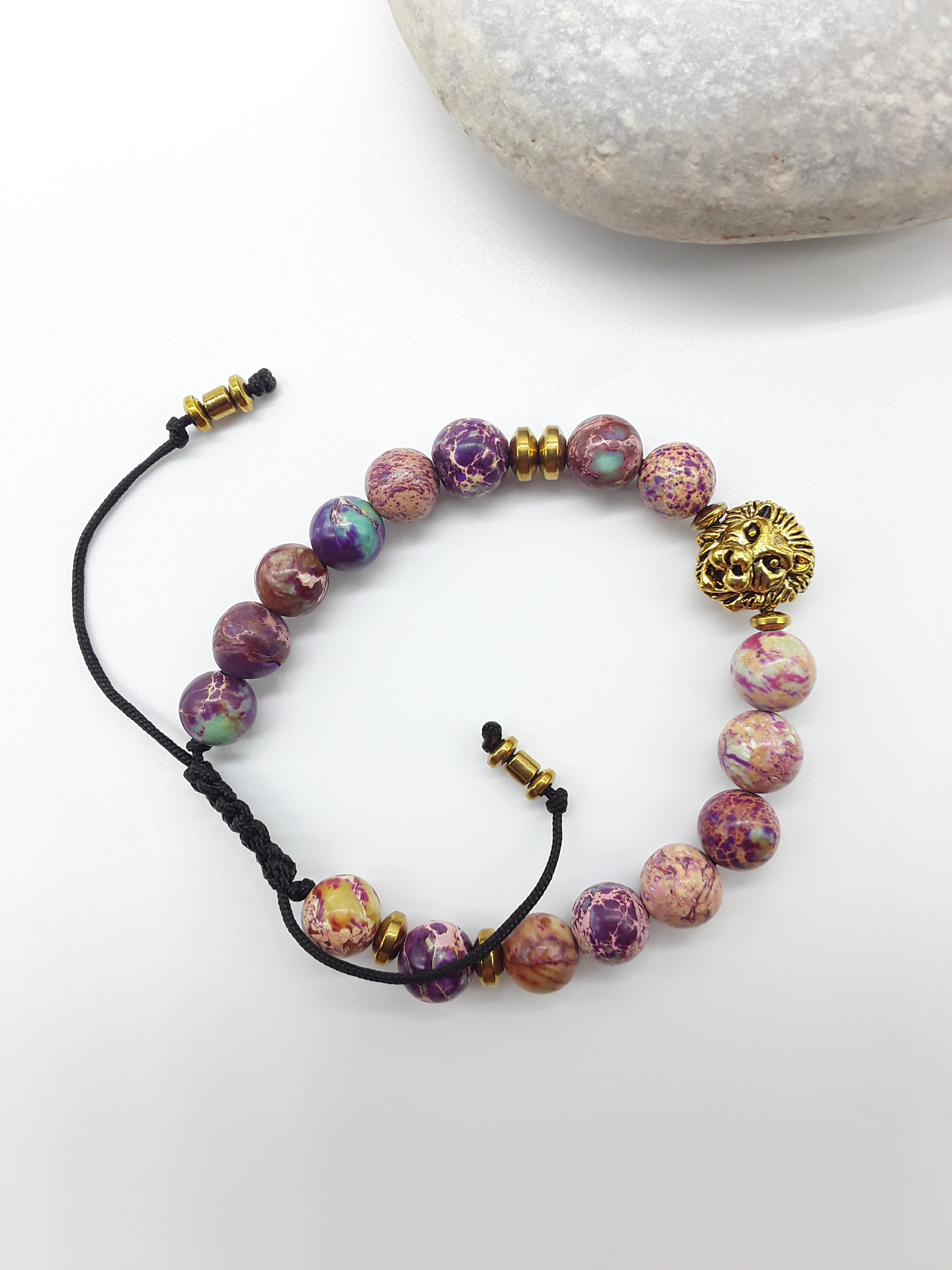Beaded lion bracelet with imperial jasper stones placed beside natural rocks