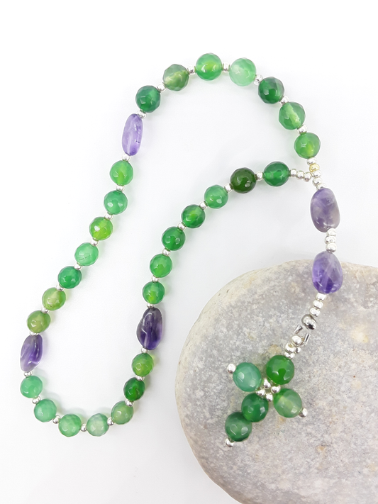 The Living Garden Anglican Prayer Beads by Polmadeva placed on stone, crafted with Agate, Amethyst, and Miyuki spacers