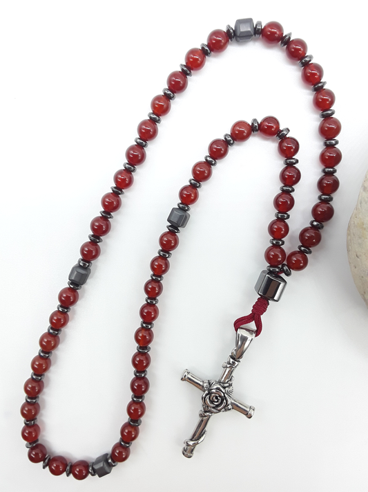 Carnelian and Hematite Orthodox Rosary with stainless steel cross beside natural stone surface by Polmadeva.