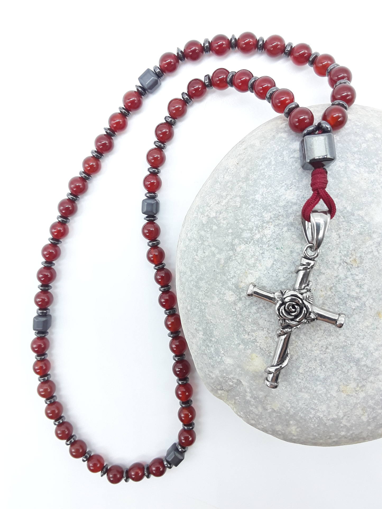 Carnelian and Hematite Orthodox Rosary with stainless steel cross resting on natural stone surface by Polmadeva.