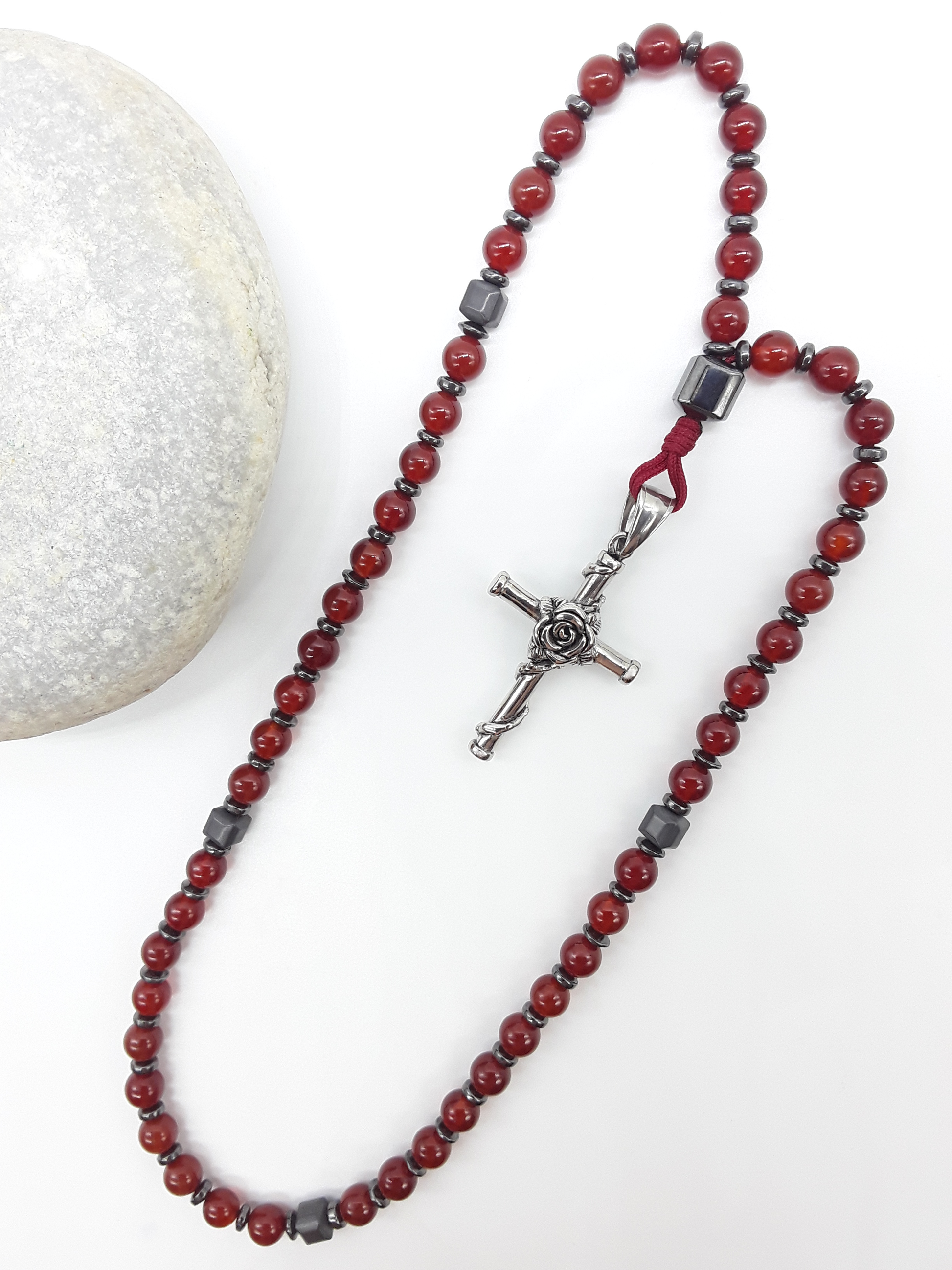 Carnelian and Hematite Orthodox Rosary with stainless steel cross beside natural stone surface by Polmadeva.
