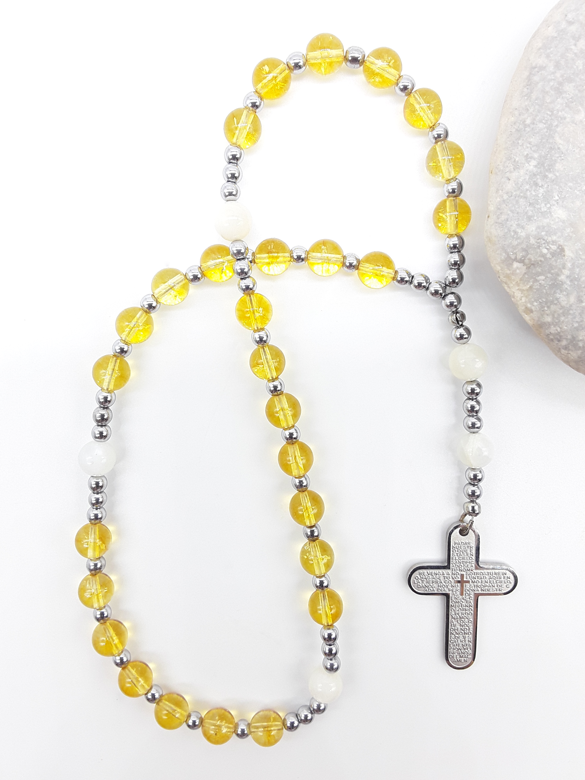 The Morning Benediction Anglican Prayer Beads by Polmadeva beside natural stone, featuring Citrine, Moonstone, Hematite, and engraved cross
