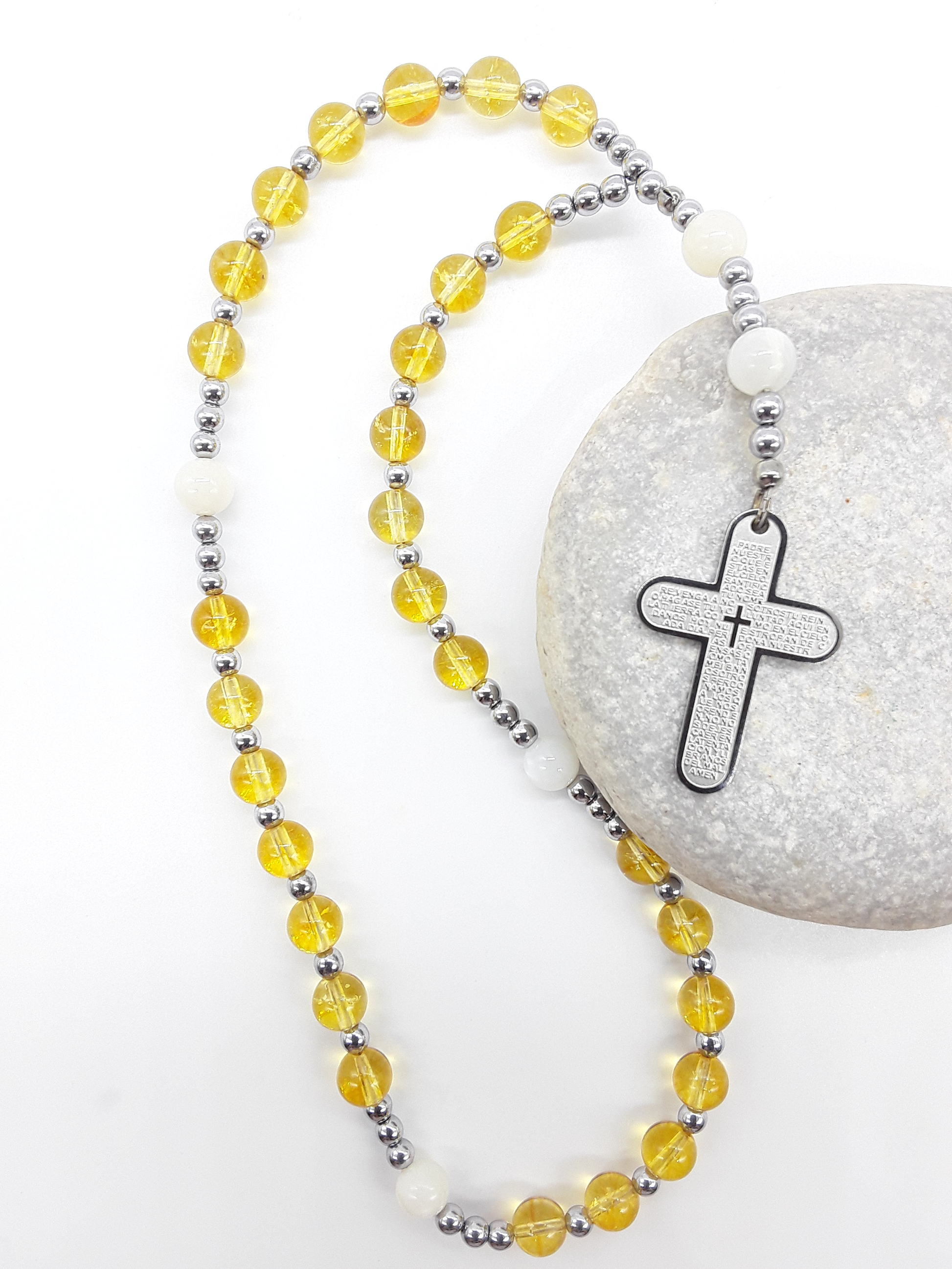 The Morning Benediction Anglican Prayer Beads by Polmadeva placed on stone, crafted with Citrine, Moonstone, Hematite, and stainless steel engraved cross