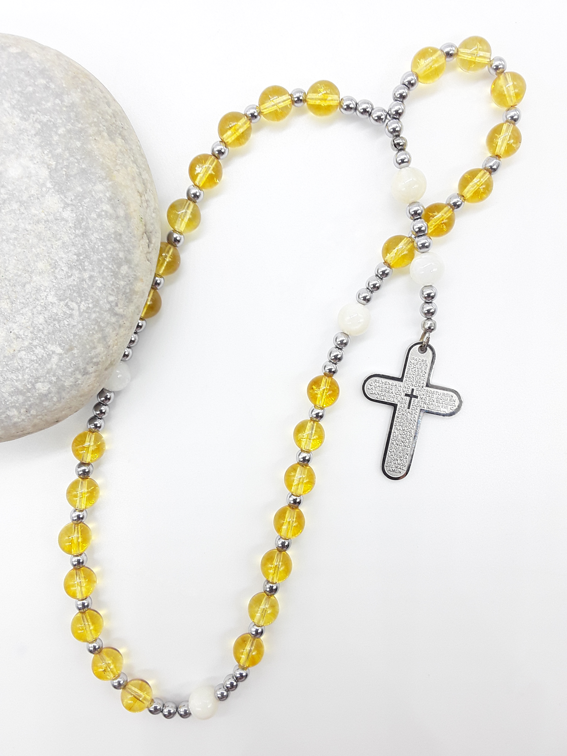 The Morning Benediction Anglican Prayer Beads by Polmadeva beside natural stone, featuring Citrine, Moonstone, Hematite, and engraved cross