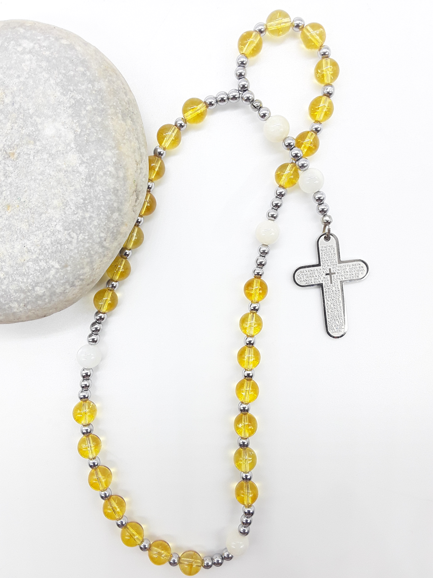 The Morning Benediction Anglican Prayer Beads by Polmadeva beside natural stone, featuring Citrine, Moonstone, Hematite, and engraved cross