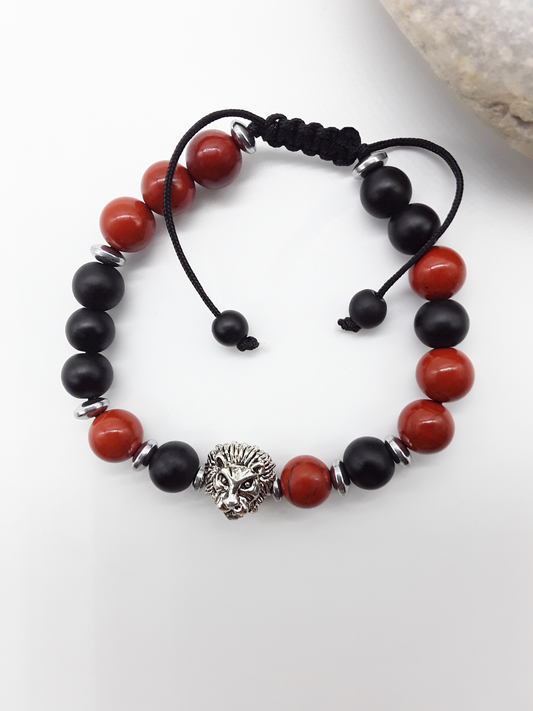 The Quiet Hold Lion Bracelet by Polmadeva placed beside natural stone, crafted with red jasper, matte onyx and hematite beads