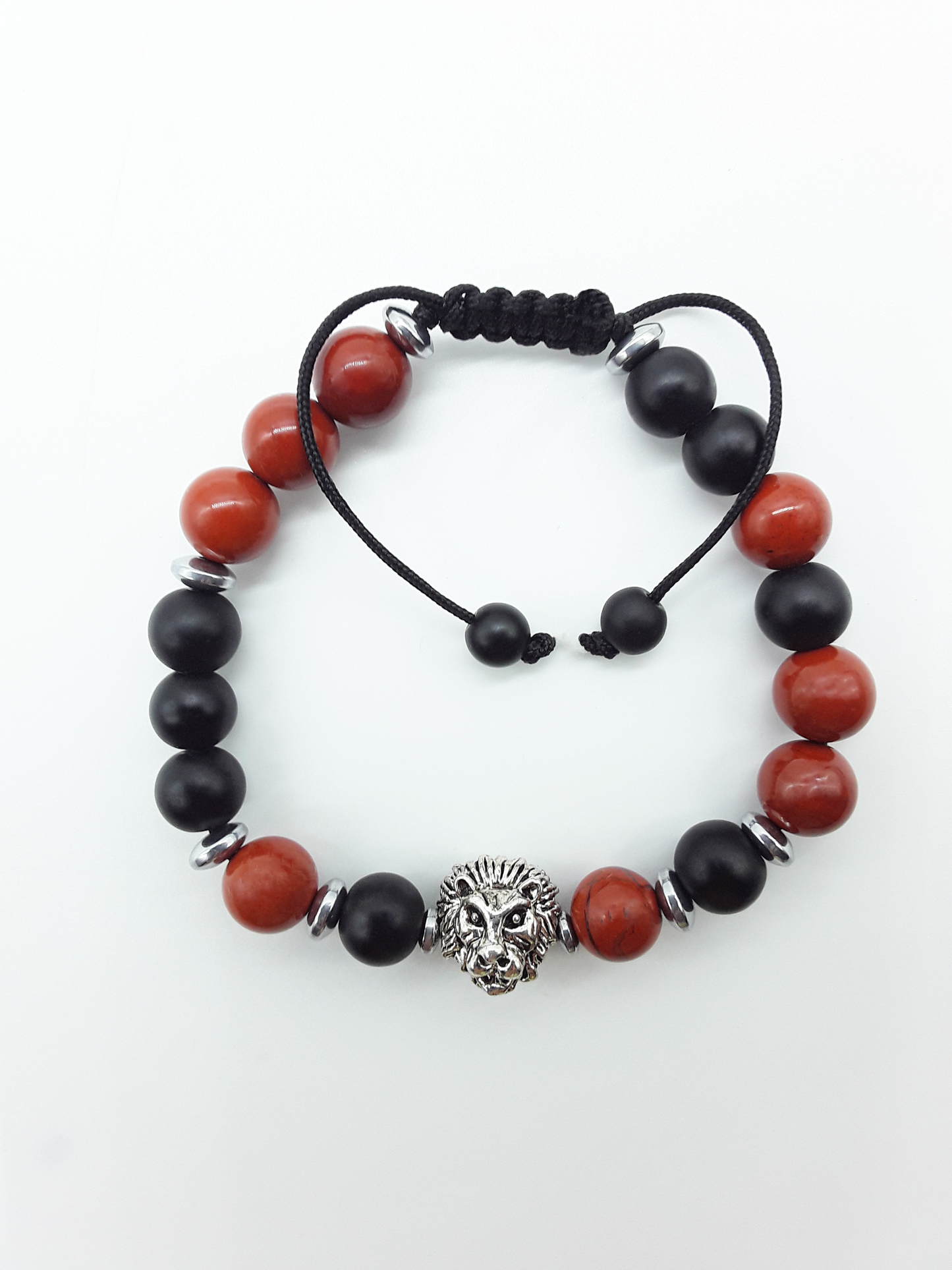 The Quiet Hold Lion Bracelet by Polmadeva with red jasper, matte onyx and hematite beads on a white background