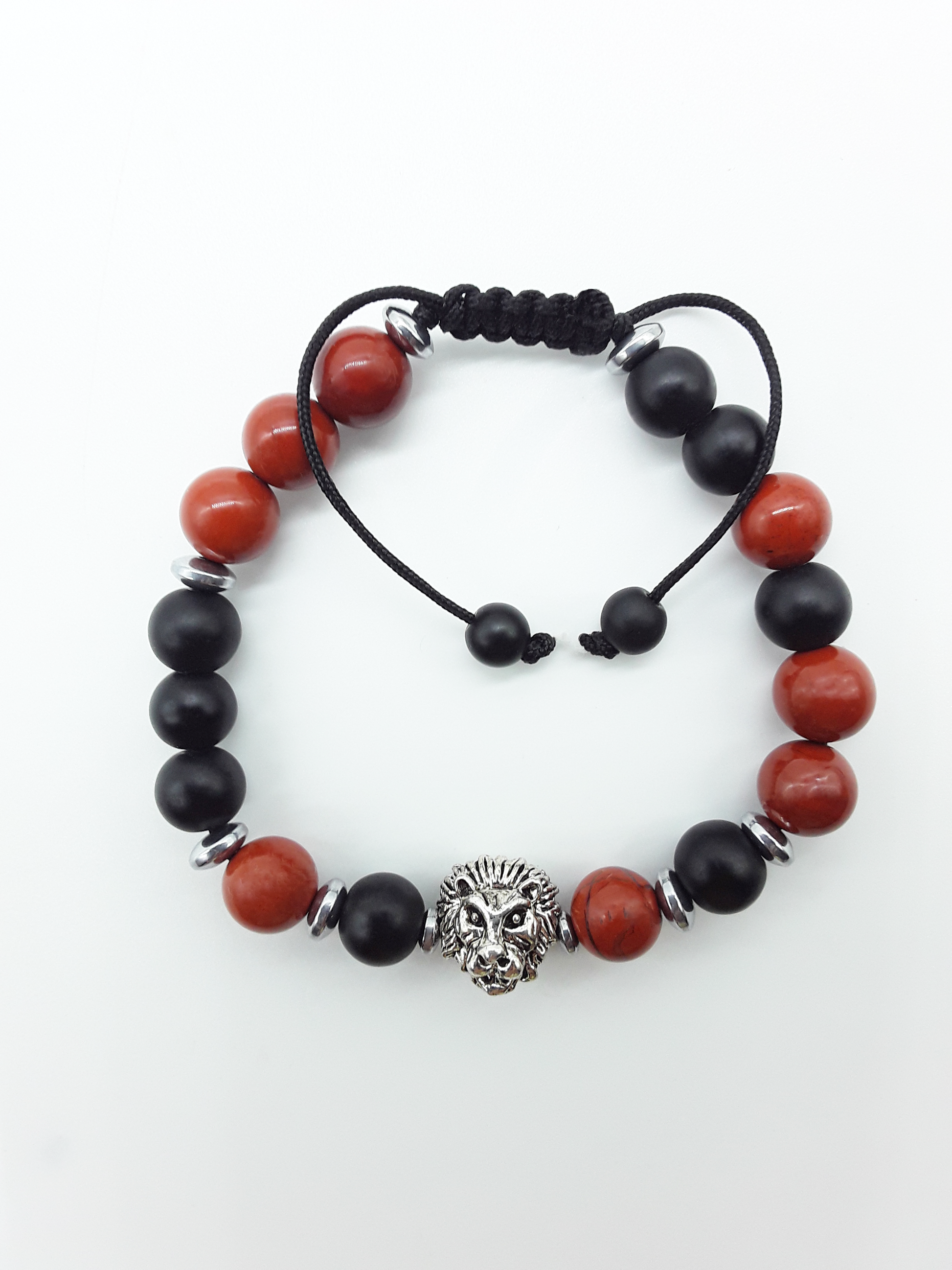 The Quiet Hold Lion Bracelet by Polmadeva with red jasper, matte onyx and hematite beads on a white background