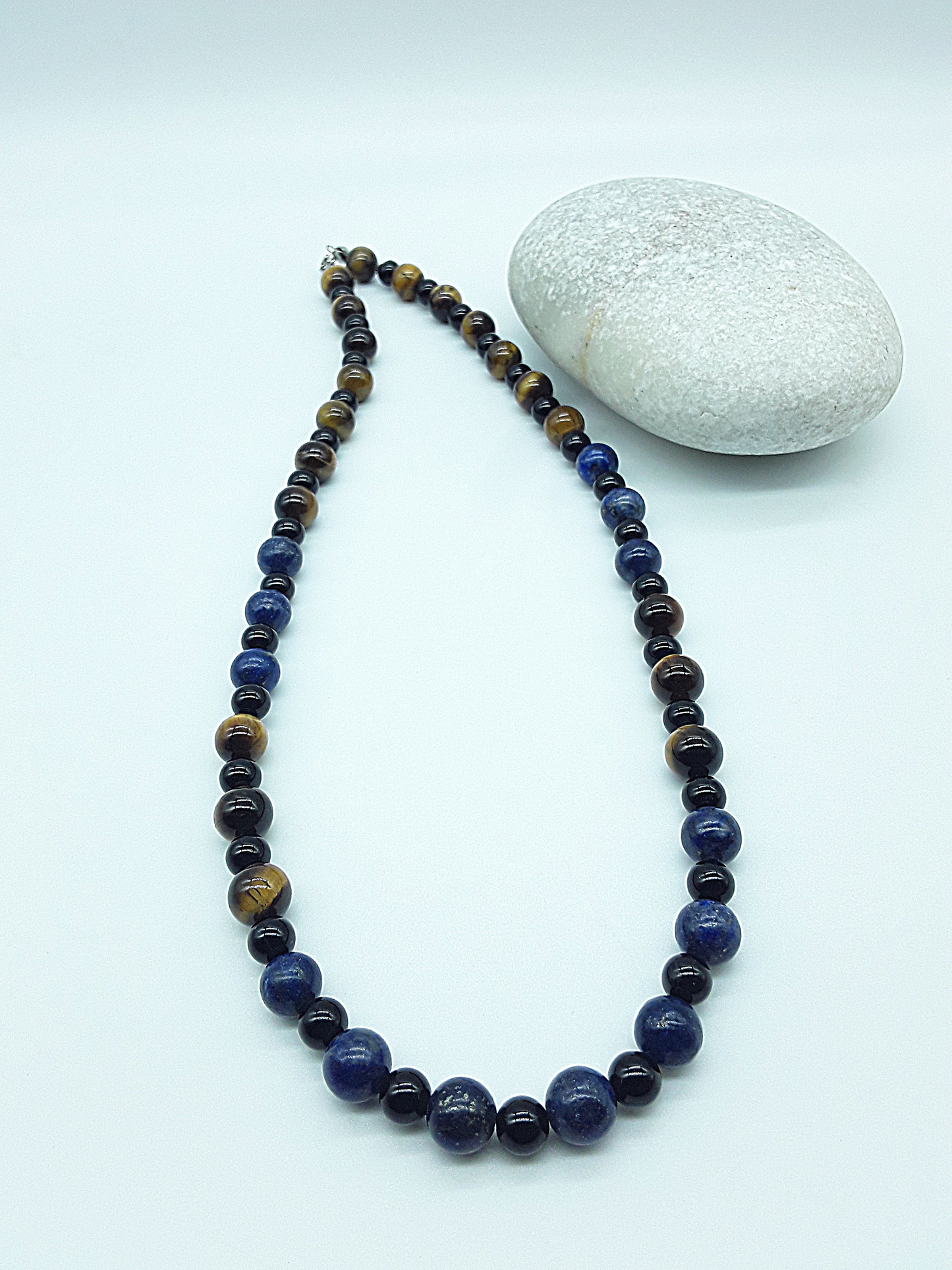 Polmadeva Quiet Sentinel Necklace with lapis lazuli, tiger’s eye and black onyx beads shown in full length beside natural stone, Guardian Spirit collection