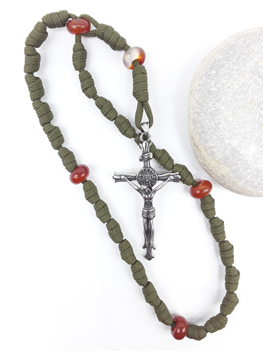 The Quiet Sentinel Paracord Anglican Prayer Beads by Polmadeva beside natural stone, featuring Carnelian and stainless steel crucifix