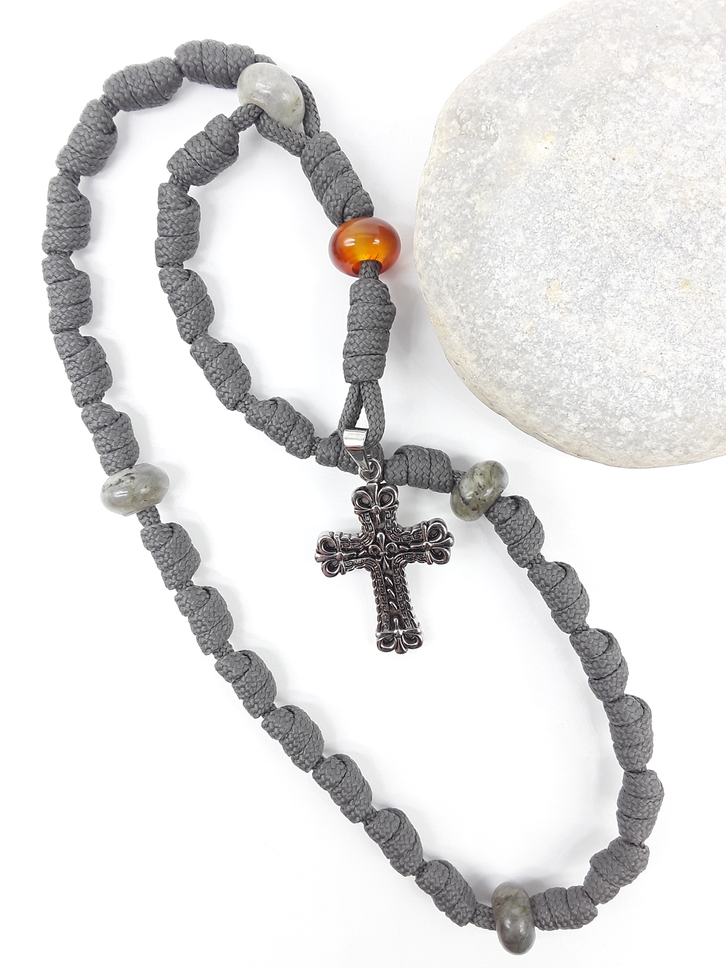 The Quiet Way Antique Floral Anglican Rosary by Polmadeva with hand-knotted cord, Carnelian and Labradorite elements, and floral stainless steel cross beside stone.