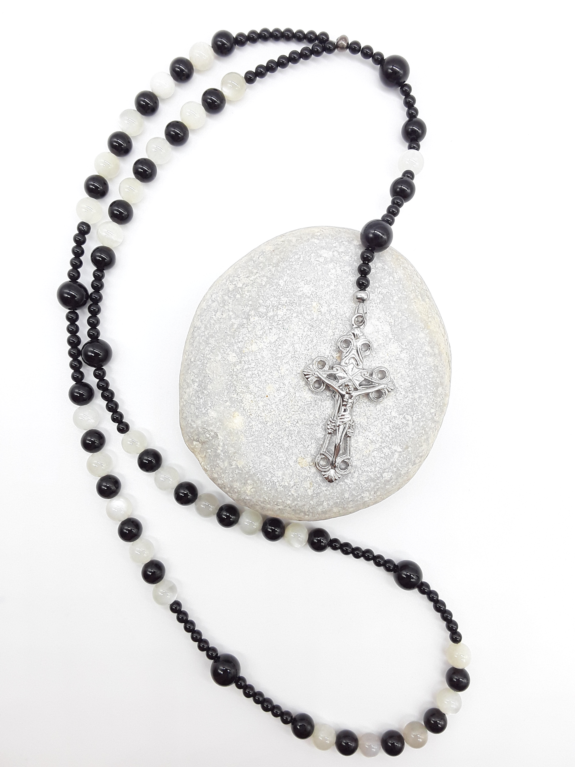 Black Onyx and Moonstone Catholic rosary with a crucifix, photographed over a natural stone on a white surface.
