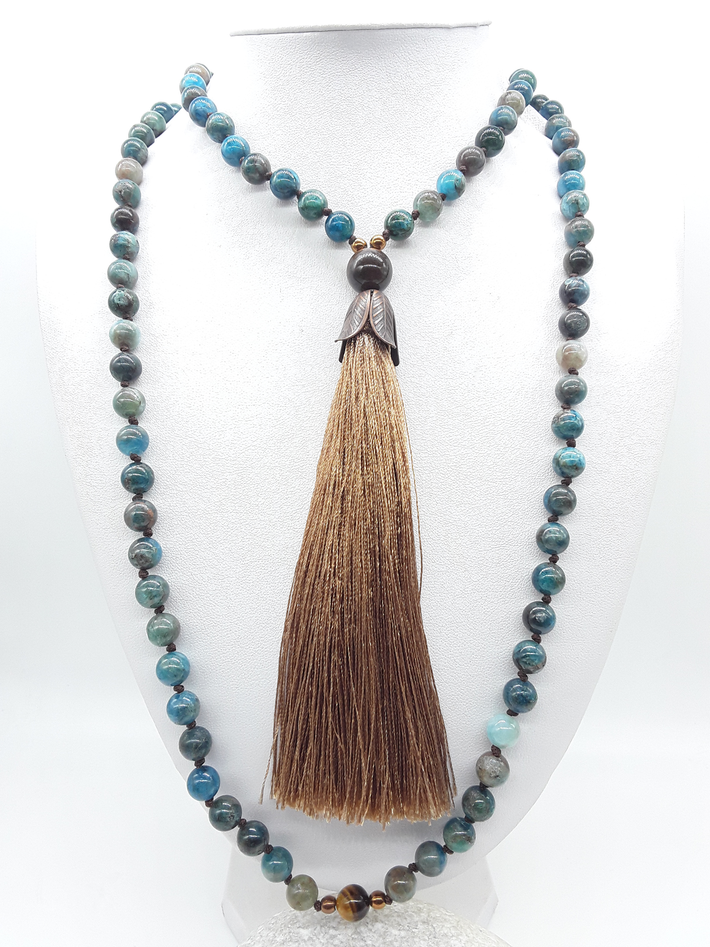 Apatite Mala Beads with Tiger’s Eye accents, Hematite elements and tassel displayed on white background, Polmadeva