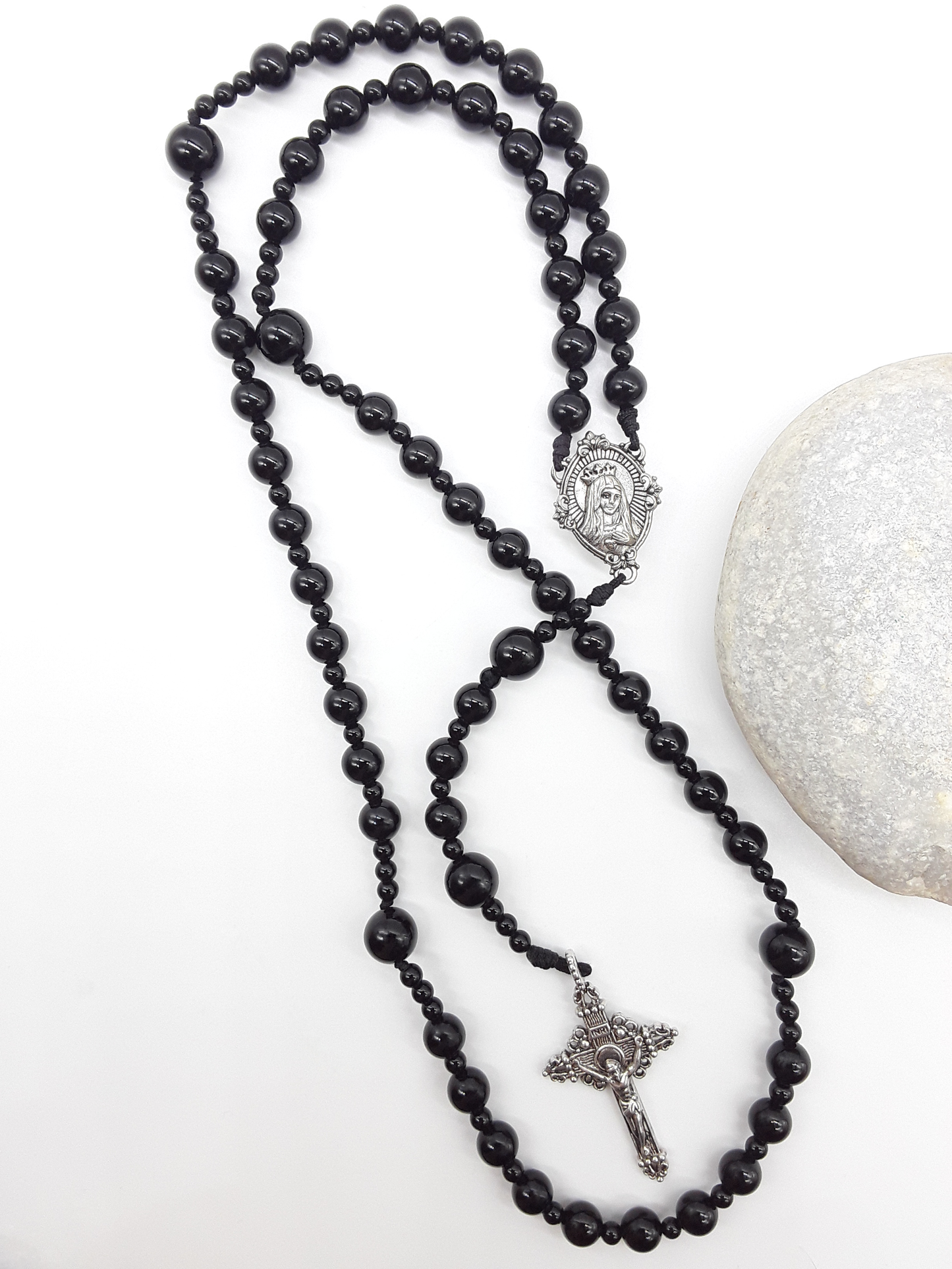 Black onyx Catholic rosary featuring a tin Virgin Mary medallion and traditional tin crucifix, arranged on a light neutral background.
