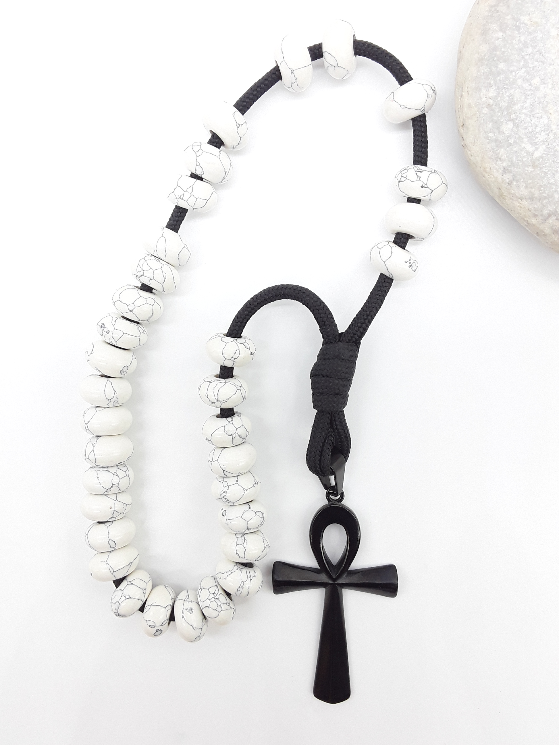 Howlite Paracord Orthodox Rosary with black Ankh cross beside natural stone surface by Polmadeva.
