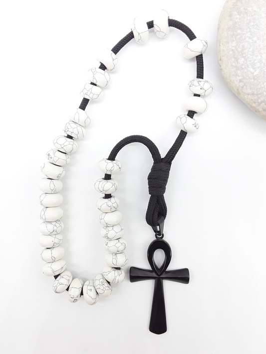 Howlite Paracord Orthodox Rosary with black Ankh cross beside natural stone surface by Polmadeva.