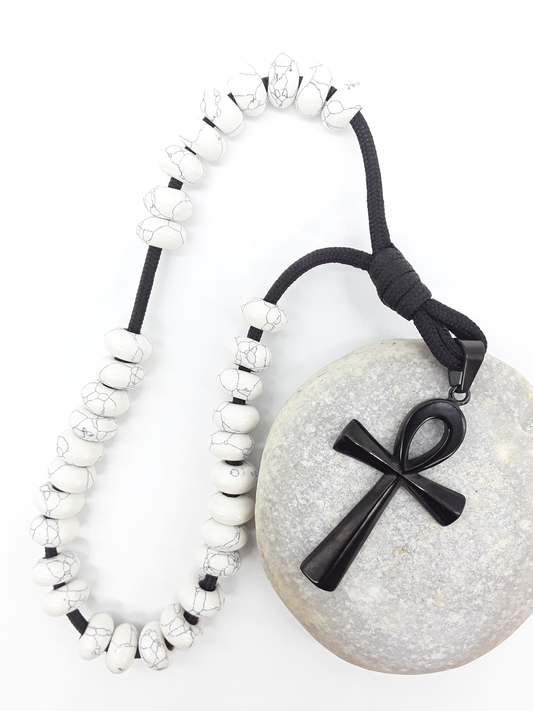 Howlite Paracord Orthodox Rosary resting on natural stone surface with black stainless steel Ankh cross by Polmadeva.