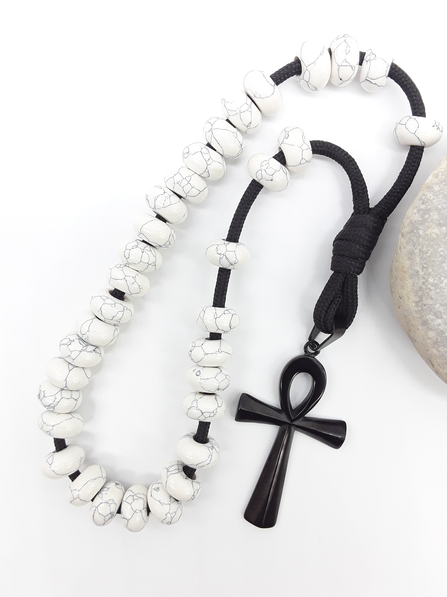 Howlite Paracord Orthodox Rosary with black Ankh cross beside natural stone surface by Polmadeva.
