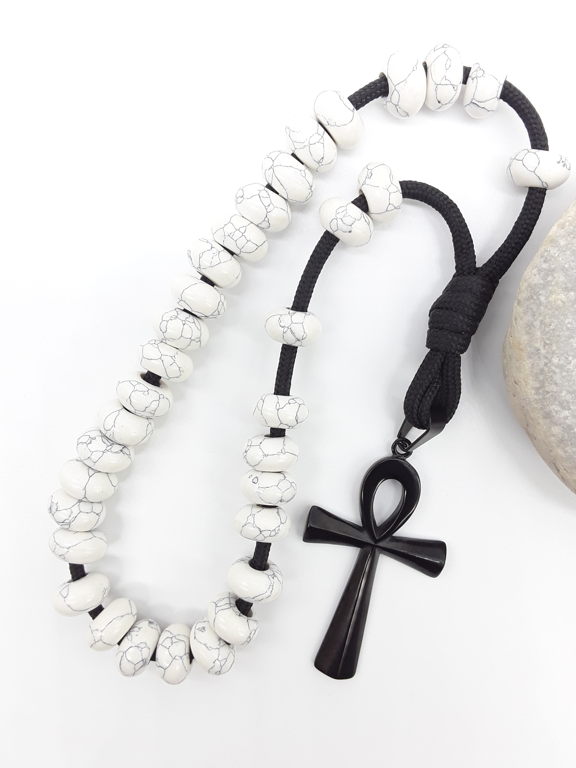 Howlite Paracord Orthodox Rosary with black Ankh cross beside natural stone surface by Polmadeva.