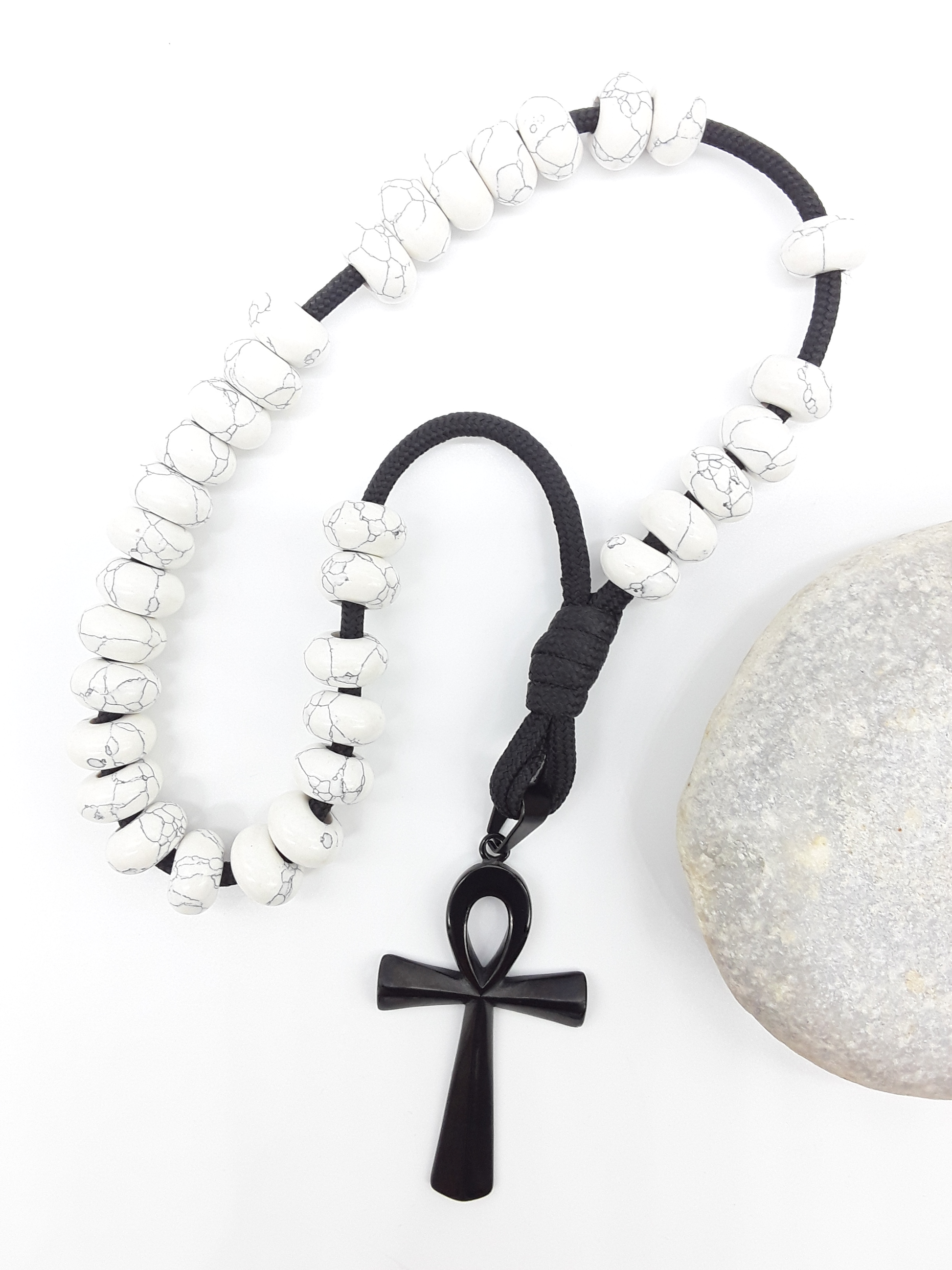 Howlite Paracord Orthodox Rosary with black Ankh cross beside natural stone surface by Polmadeva.