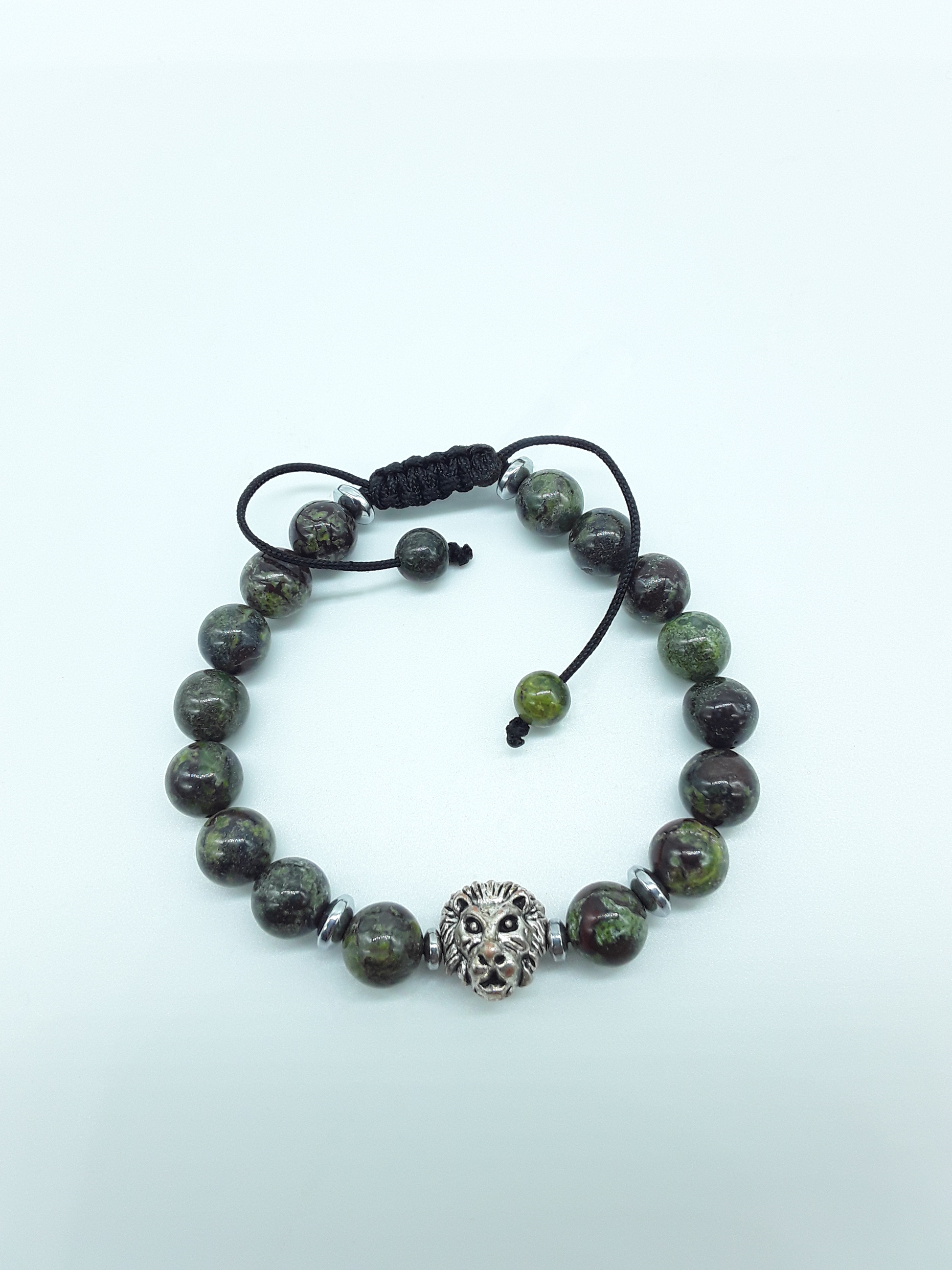 Handcrafted beaded bracelet with natural dragon blood stone beads and a metal lion centerpiece on a light neutral background