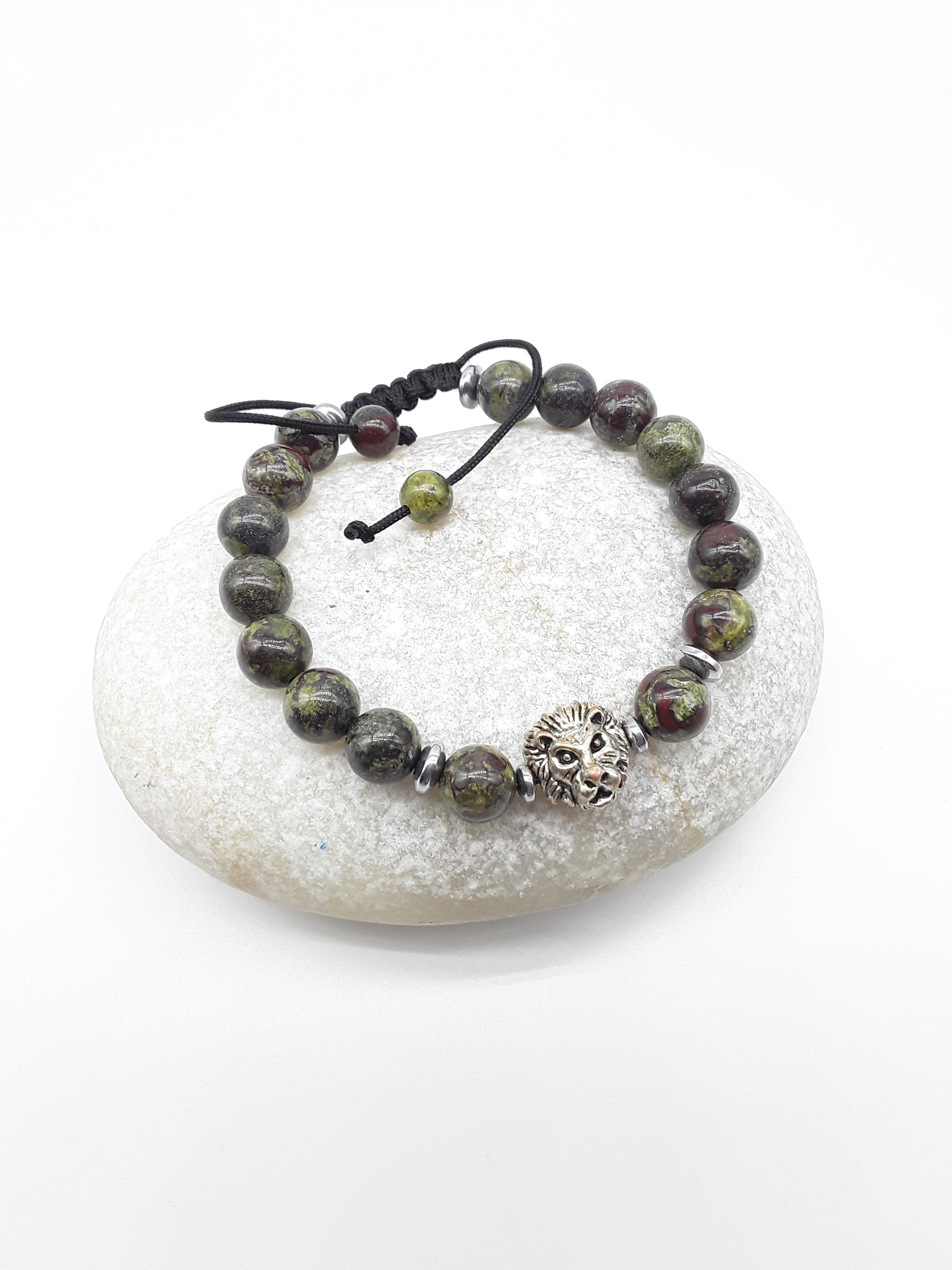 Beaded bracelet made of natural dragon blood stones with a metal lion detail, shown on a smooth stone background