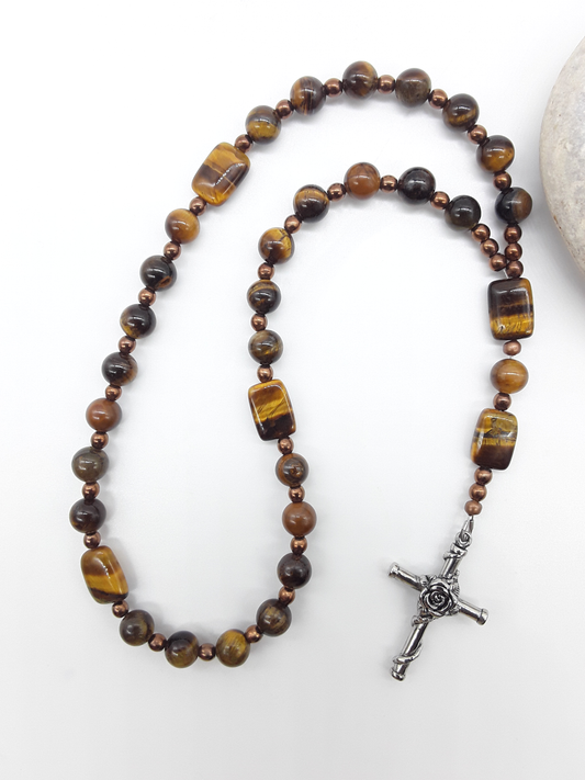 The Steady Gaze Anglican Prayer Beads by Polmadeva beside natural stone, featuring Tiger’s Eye, Hematite, and Rosicrucian Cross
